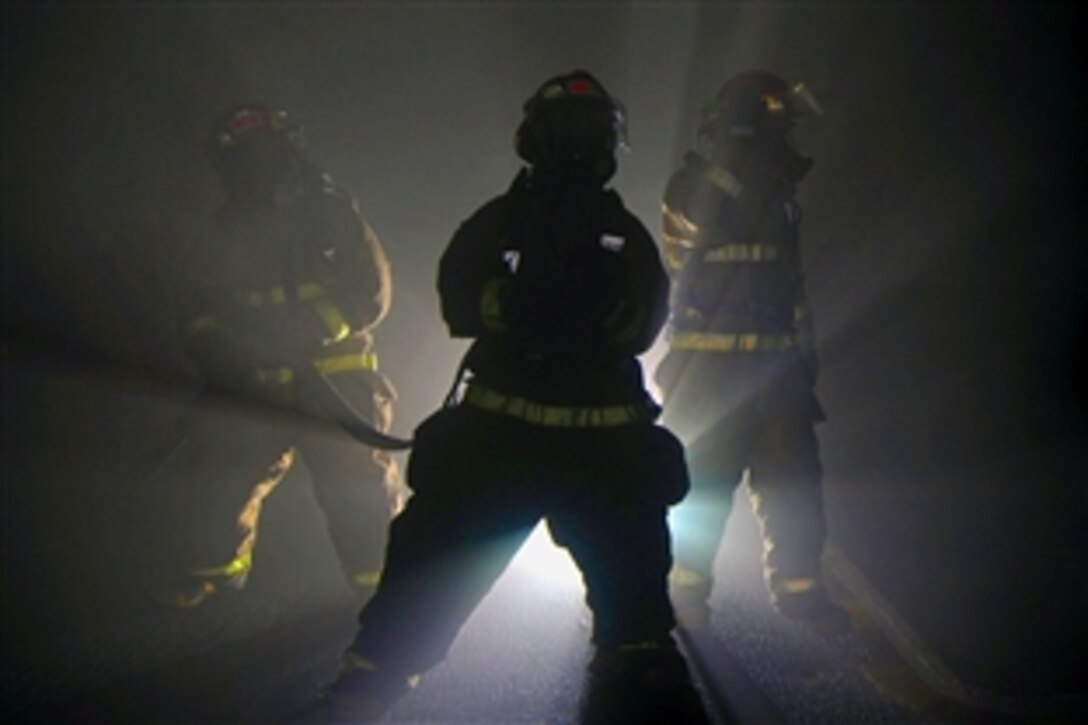 U.S. Navy sailors simulate fighting a fire in the hangar bay aboard the USS Abraham Lincoln during a general quarters drill, Pacific Ocean, April 9, 2009. With the use of a smoke machine, sailors were exposed to what a situation with limited visibility might be like.