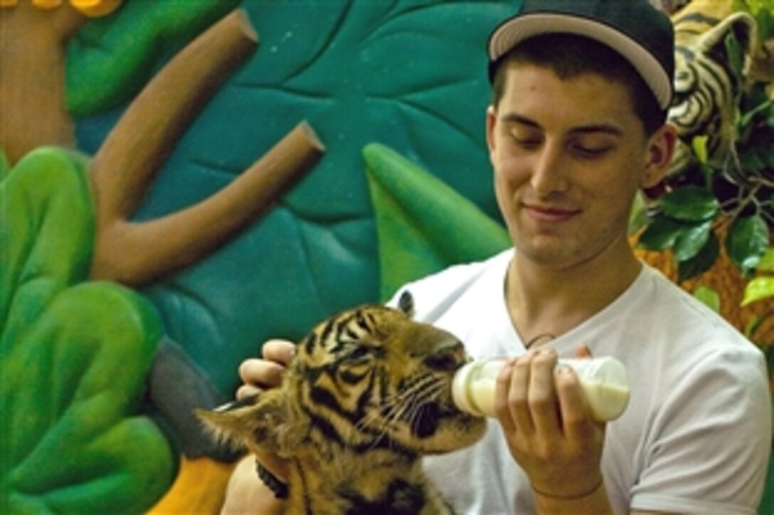 U.S. Navy Seaman Julian Lugo, assigned to the aircraft carrier USS John C. Stennis, feeds an adolescent tiger at the Sriracha Tiger Zoo in Pattaya, Thailand, April 11, 2009. The USS Stennis is in Thailand on a scheduled port visit as part of its six-month deployment to the Western Pacific Ocean.