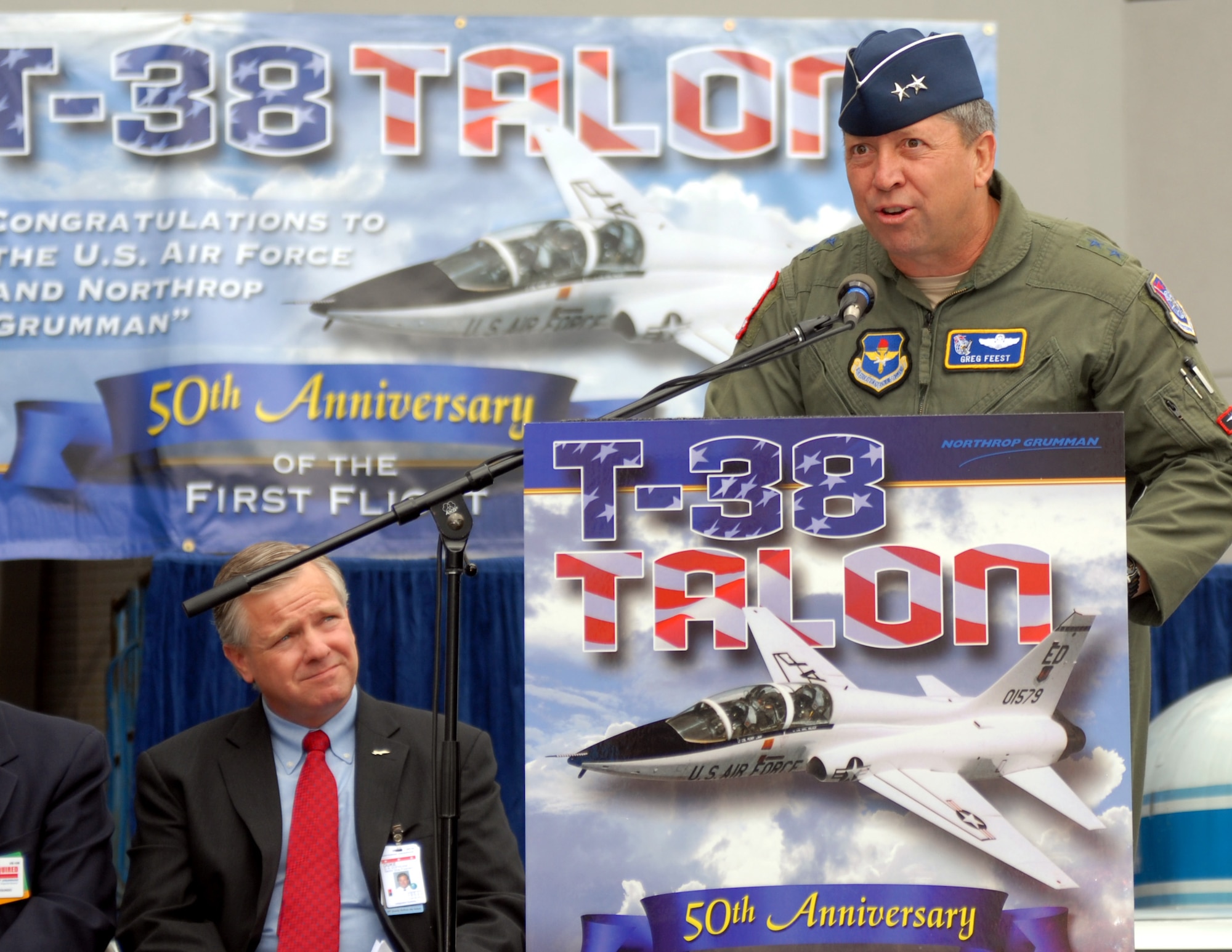 Maj. Gen. Greg Feest, 19th Air Force commander at Randolph Air Force Base, Texas, speaks at the Northrop Grumman facility in El Segundo, Calif., April 10 during the commemoration of the T-38 Talon?s first flight fifty years ago on April 10, 1959.  Duke Dufresne (seated), sector vice president and general manager of the Strike and Surveillance Systems division of Northrop Grumman Aerospace Systems, also provided remarks during the event. (U.S. Air Force photo by Michael Briggs)