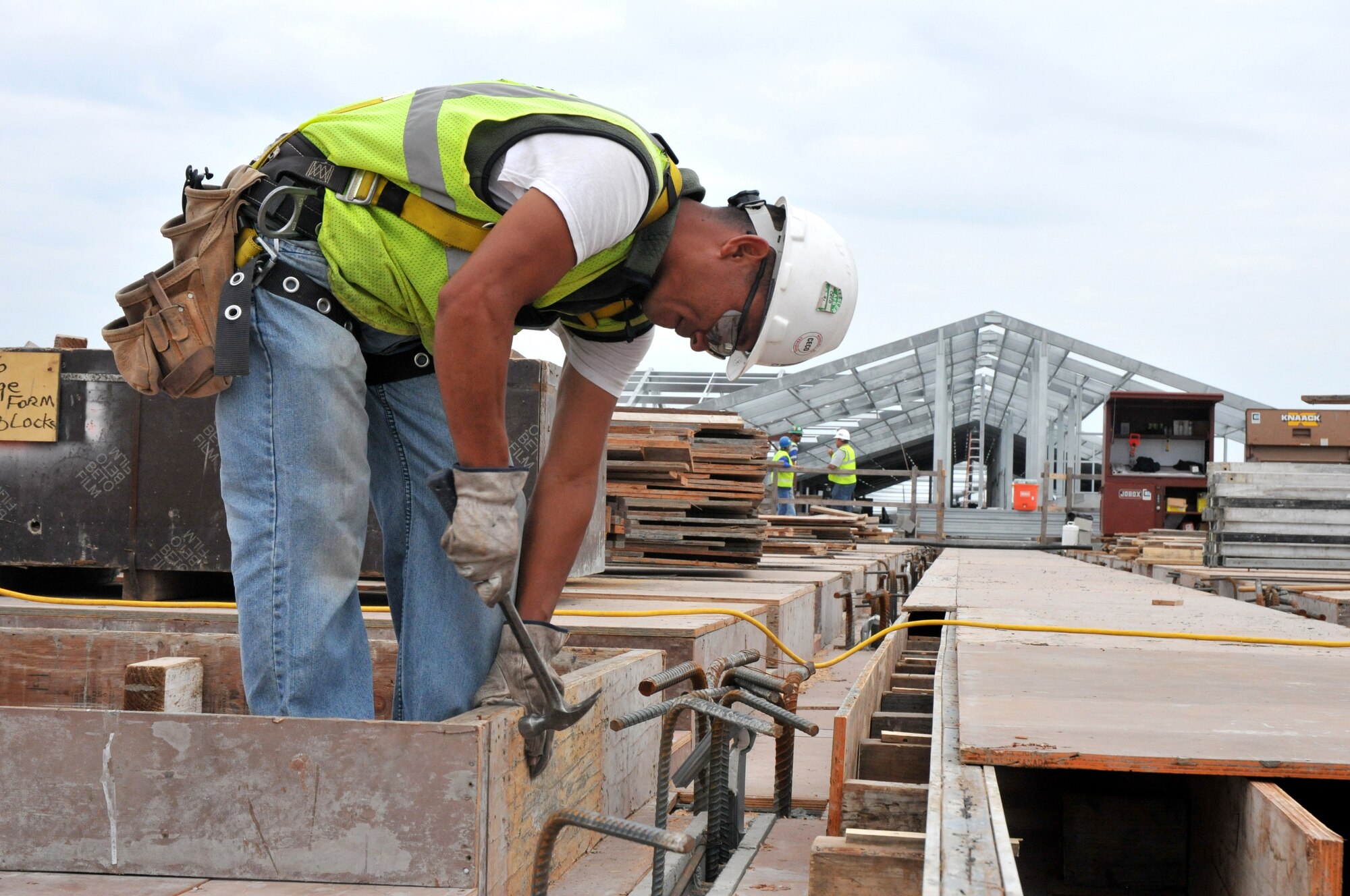 David Fernandez sets forms for the attic floor on the east end of the dorm.  Concrete masonry units are being installed on the east end of the fourth floor, and metal studs are being placed on the lower floors of the east wing.  (U. S. Air Force photo by Adam Bond)