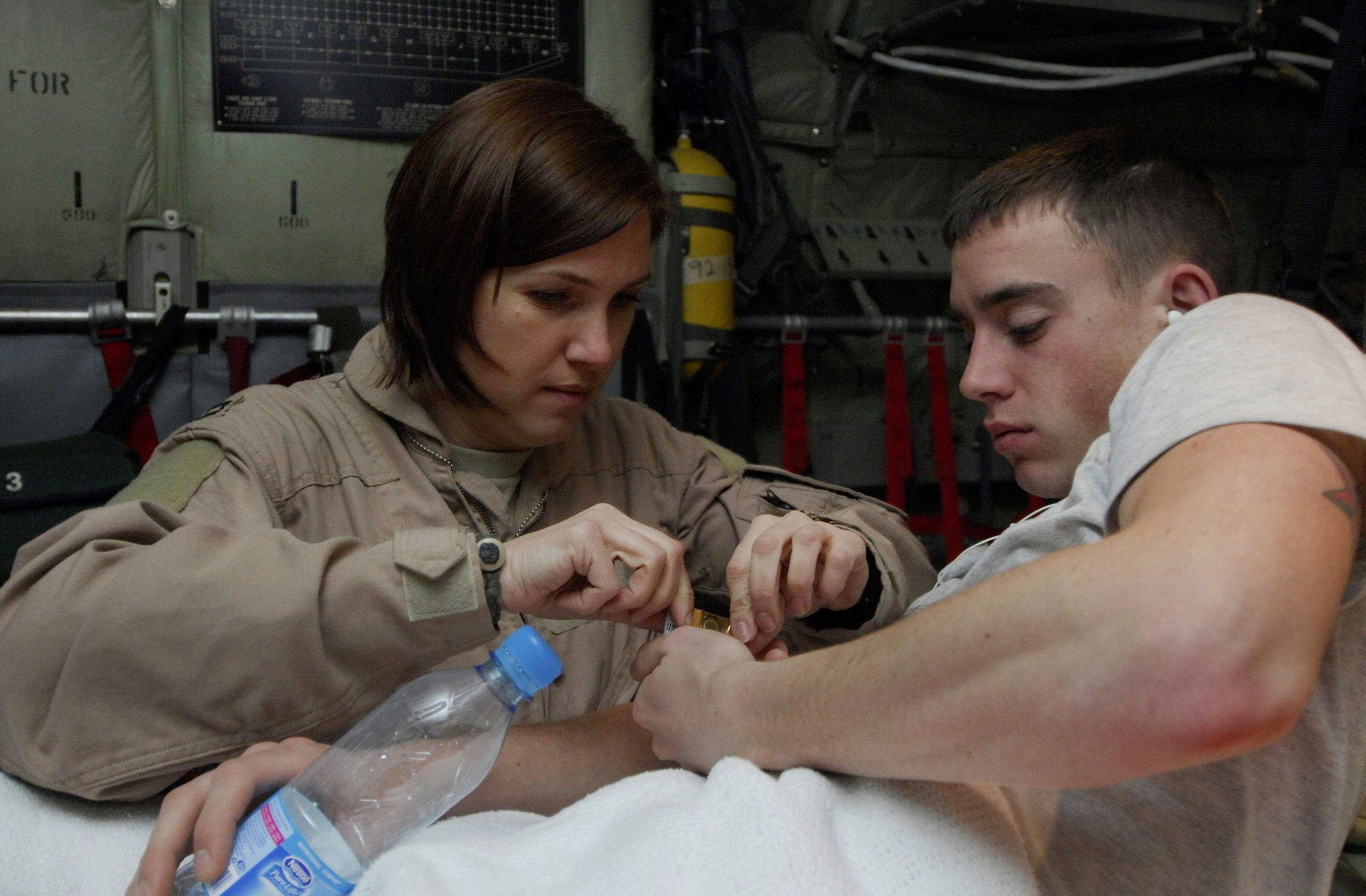 Capt. Susan McCormick gives medicine to Airman 1st Class Brent Noah March 26 during an aeromedical evacuation flight to Bagram Airfield, Afghanistan.  Airman Noah, assigned to the 376th Expeditionary Aircraft Maintenance Squadron at Manas Air Base, Kyrgyzstan, dislocated his hip and was being flown to Bagram Airfield for treatment.  Captain McCormick is a flight nurse with the 455th Expeditionary Aeromedical Evacuation Flight at Bagram.  (U.S. Air Force photo/Senior Airman Erik Cardenas)