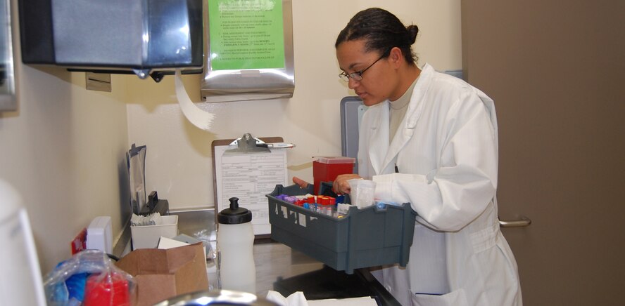 Senior Airman Tambara Hamilton gathers up the blood collection tray before heading to the primary care clinic to obtain a patient's blood April 9. (U.S. Air Force photo/Valerie Mullett)