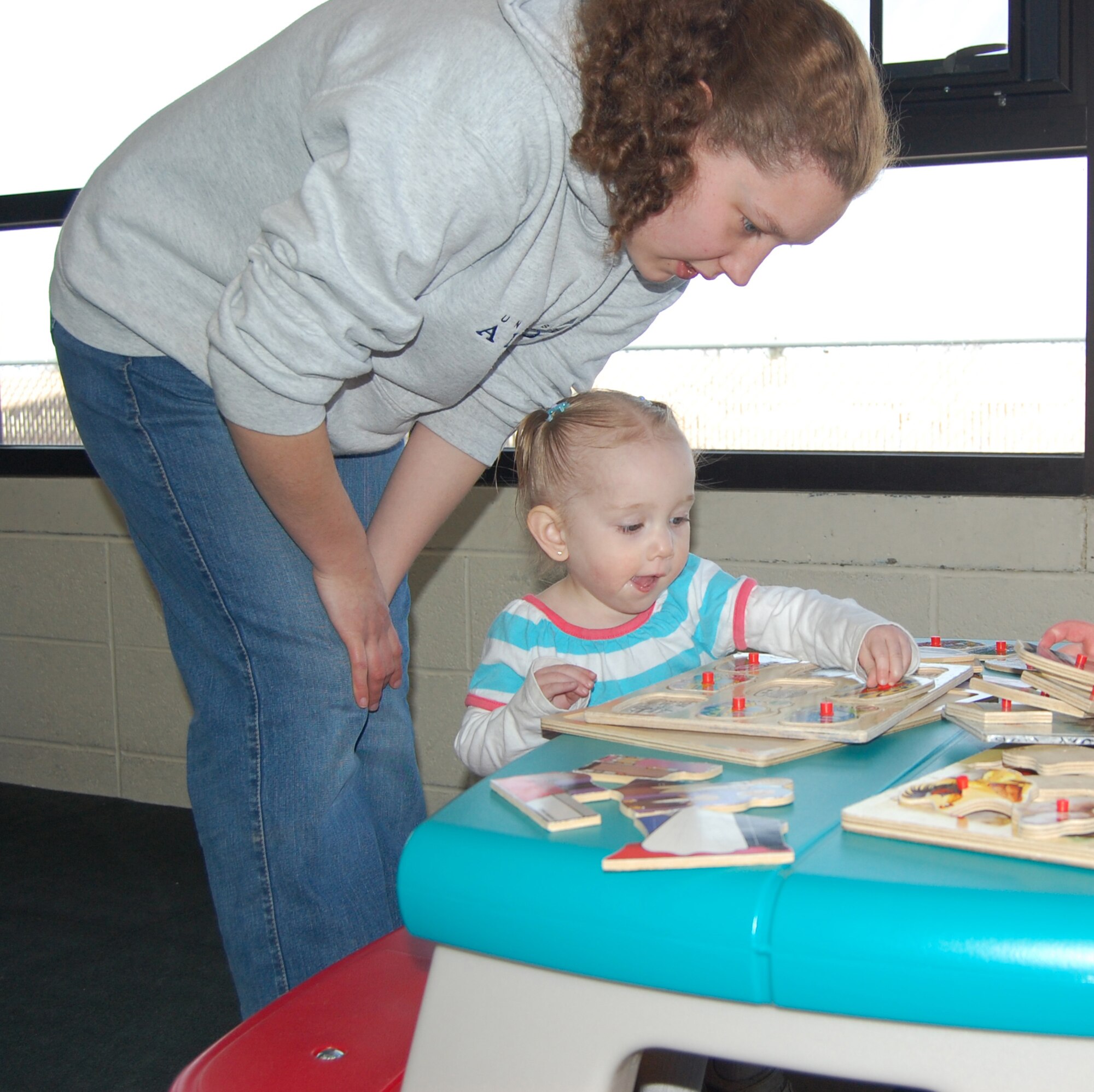 Family Child Caregiver Leanne Ward helps 21-month-old Abigail with a puzzle prior to the start of a luncheon in their honor April 10. April is Month of the Military Child. (U.S. Air Force photo/Valerie Mullett)