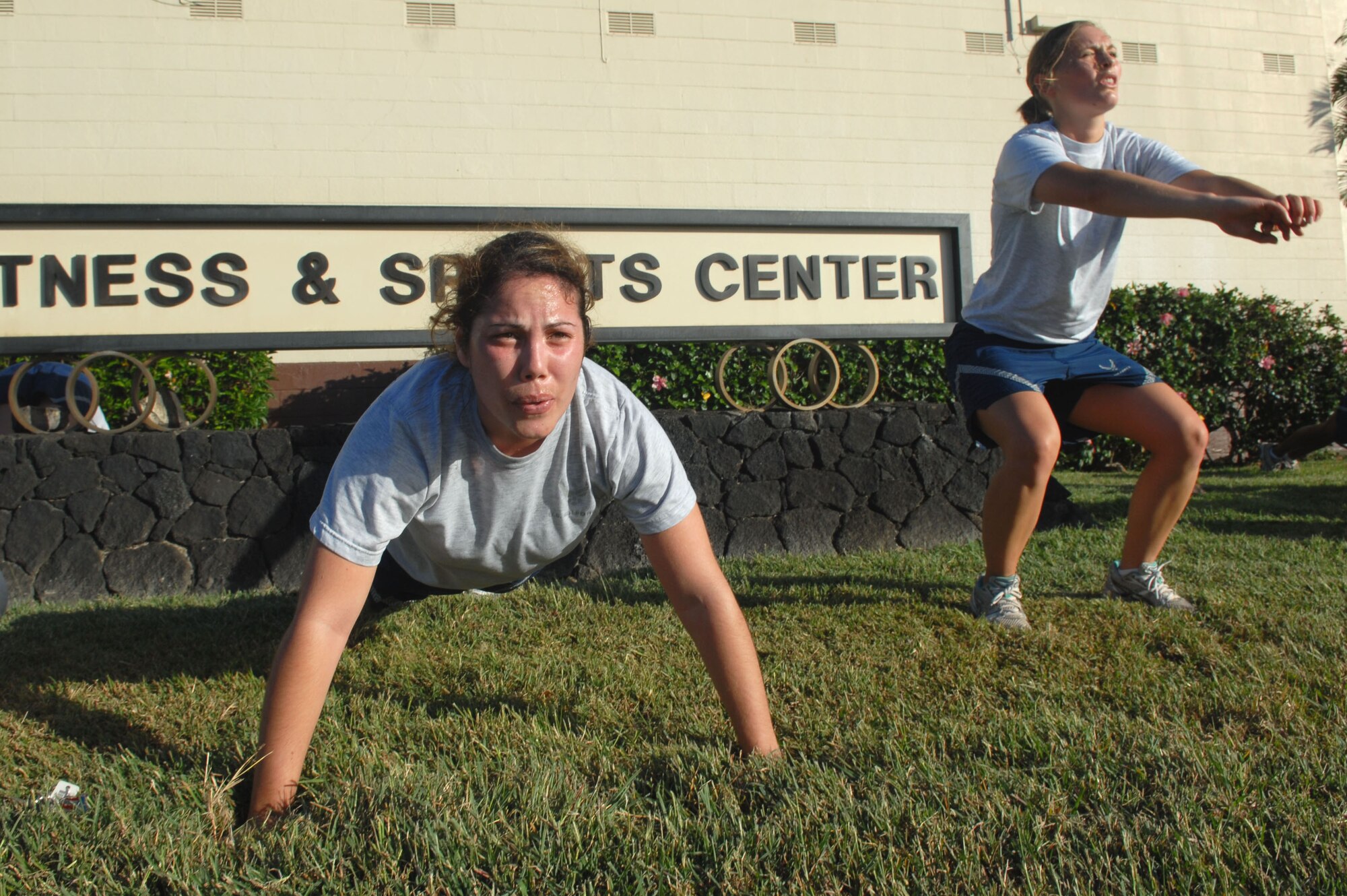 HICKAM AIR FORCE BASE, Hawaii -- Staff Sgt. Zenaida Johnson does push-ups while 1st Lt. Lisa Kempker does squats during 15th Comptroller Squadron PT April 14. (U.S. Air Force photo by Ed Foster)