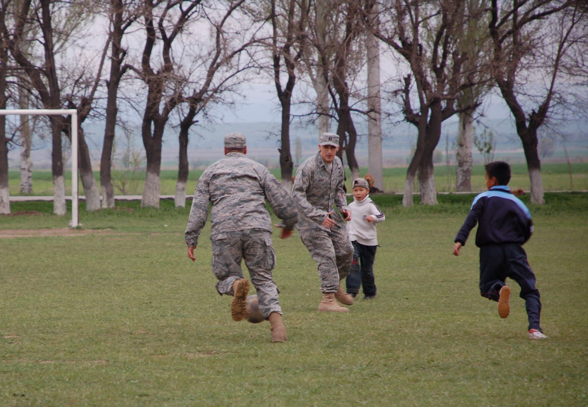 Following a ground breaking ceremony at Birdik Village School in Kyrgyzstan students from the school challenge Airmen from nearby Manas Air Base to an impromptu game of soccer, April 14. The Airmen were no match for the Kyrgyz children's sheer numbers, agility and speed, and ended the exciting game, 2-3. The ground breaking ceremony kicked off a six-month, $470,000 project to renovate the school, currently a shell of a building. Funded by the U.S. Central Command and managed by Airmen from Manas AB, the project is scheduled for completion in Autumn 2009 and will provide a quality learning environment for 200 students. A local Kyrgyz company, Imarat Stroy, was awarded the contract March 17 and has already gutted the building in preparation for the rebuilding effort. (U.S Air Force photo/Tech. Sgt. Phyllis Hanson)  