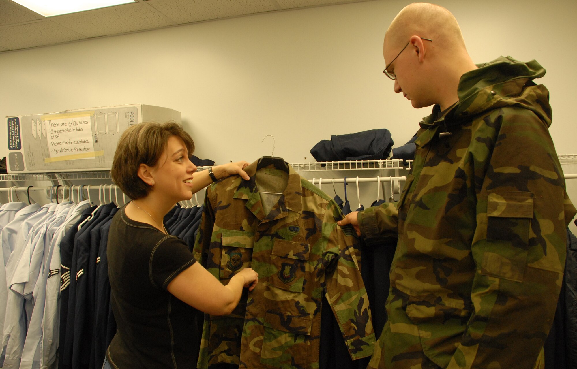 (Left to right) Dana Mickley, Airman's Attic director, and wife of Maj. William Mickley, 436th Airlift Wing, showcases a used Battle Dress Uniform to Airman 1st Class Ben Krotke, 436th Aircraft Maintenance Squadron, at the Airman's Attic. The Airman's Attic is a volunteer-run base organization that offers Dover Airmen and their families new and used donated items. (U.S Air Force photo/Airman 1st Class Shen-Chia Chu)