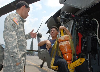 SOTO CANO AIR BASE, Honduras - Army Specialist Juan Perez-Fernanzez, 1-228th Aviation Regiment, shows Ever Aviles the hoist on a UH-60 Blackhawk helicopter during a Honduran air show in Tegucigalpa, April 14.  Specialist Perez-Fernandez is a Blackhawk flight engineer assigned to Joint Task Force-Bravo here.  The unit supported the airshow with a helicopter as a static display and a medical team.  (U.S. Air Force photo/Tech. Sgt. Rebecca Danét) 