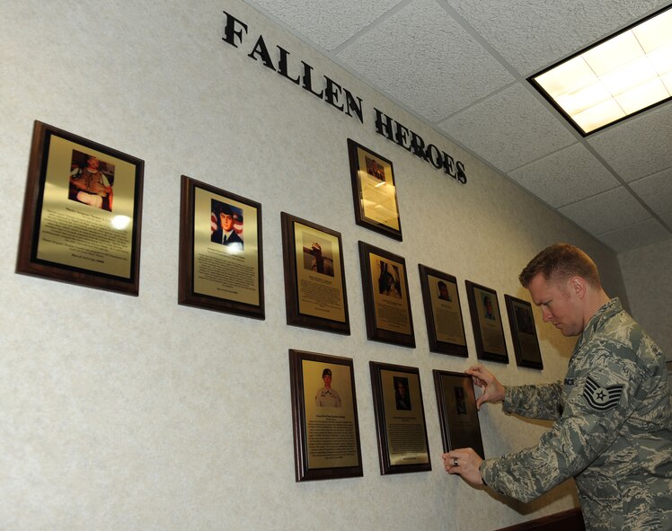 SCOTT AIR FORCE BASE, Ill. --Tech Sgt. Eric Matzek, ALS instructor, adjusts fallen heroes plaques at the Chief Master Sergeant of the Air Force Bud Andrews Airman Leadership School.  Current Airmen on the Fallen Heroes Wall are Staff Sgt. Matthew Kuglics, Master Sgt. Thomas Crowell, Airman 1st Class Raymond Losano, Master Sgt. Brad Clemmons, Airman 1st Class Jason Nathan, Staff Sgt. Jacob Frazier, Staff Sgt. Scott Sather, Staff Sgt. John Self, Airman 1st Class Elizabeth Jacobson, Senior Airman Jason Cunningham and Airman 1st Class Antoine Holt.(U.S. Air Force photo/Staff Sgt. Paul Villanueva II)