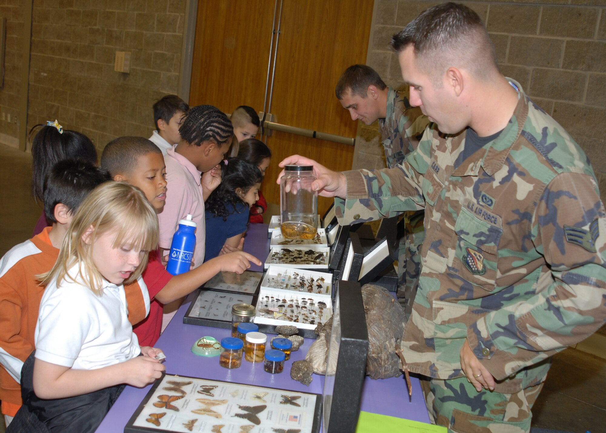 Senior Airman Andrew Carr and Staff Sgt. Zachariah Bingham of the 82nd Civil Engineering Squadron speak to children from a mixture of local schools in observance of Earth Day April 14 at the Multi-Purpose Event Center in Wichita Falls, Texas.  Airman Carr and Sergeant Bingham talked to the children about the different types of insects and arachnids that their exhibit displayed. (U.S. Air Force photo/Lou Anne Sledge)