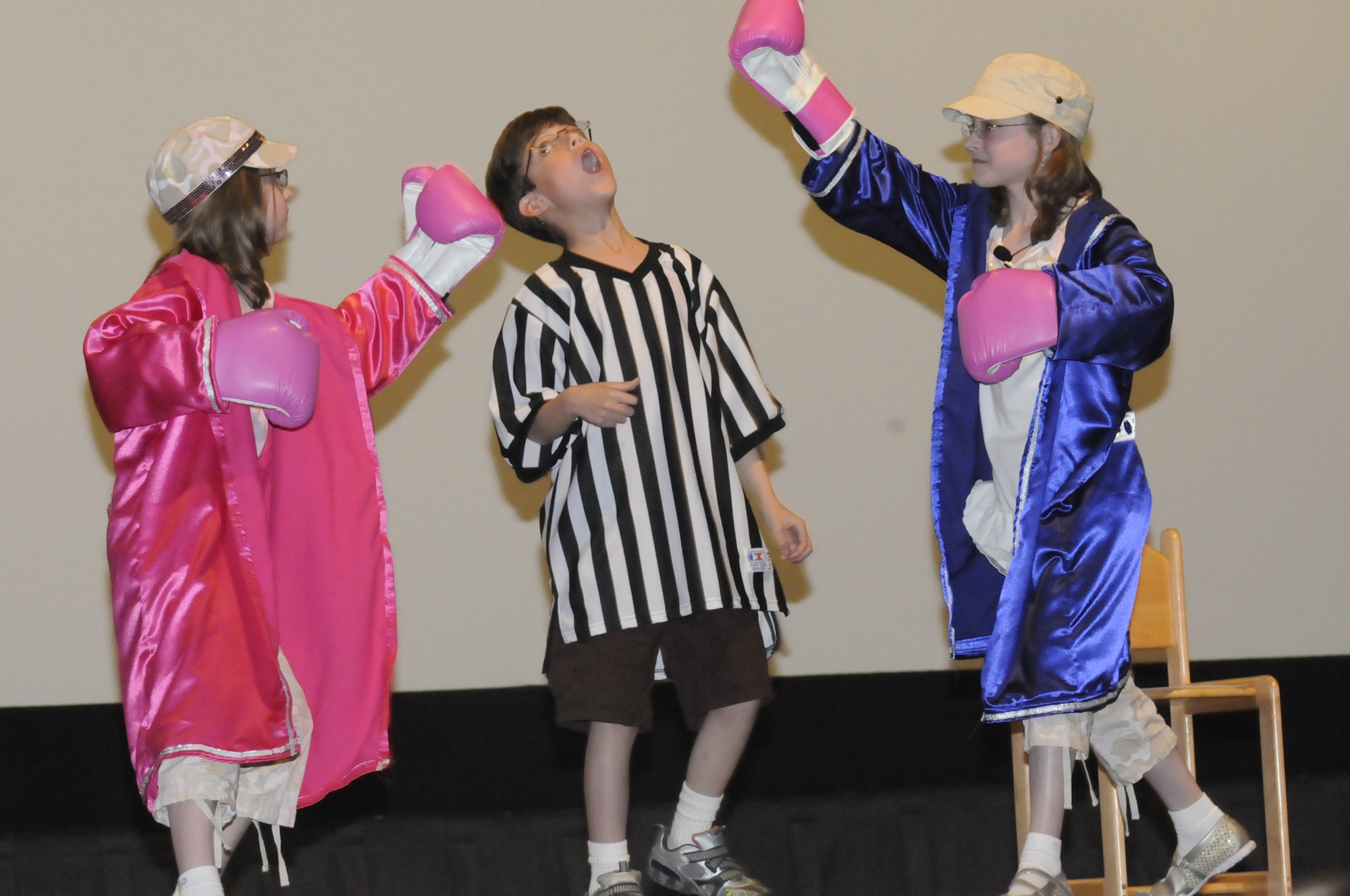 Singing twins Ariel and Zoey pretend to beat up their younger brother Eli while performing "Hit me with your best shot". U. S. Air Force photo by Sue Sapp