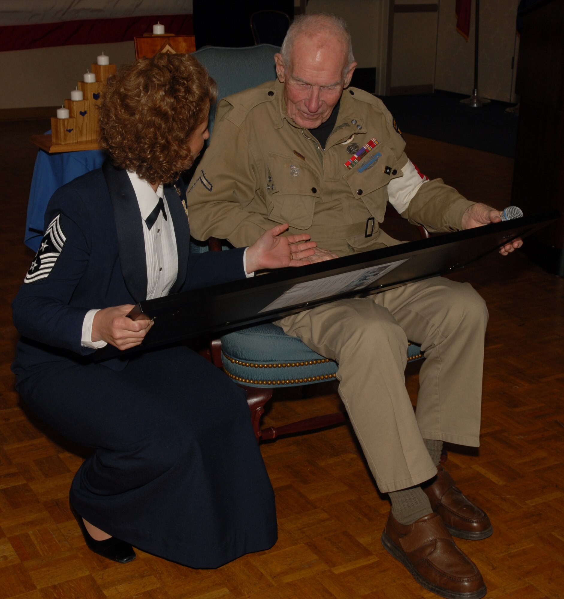 VANDENBERG AIR FORCE BASE, Calif.-- Chief Master Sgt. Cari Kent, the 30th Space Wing Command Chief,  shares a gift with guest speaker Edwin 'Doc' Pepping to express appreciation during the Chief Master Sergeant Induction Ceremony April 9  at the Pacific Coast Club here. The ceremony welcomed Vandenberg's newest chiefs to the highest enlisted grade in the Air Force.  Mr. Pepping, a World War II veteran and Bronze Star recipient, spoke during the ceremony to the two newly inducted chiefs about the importance of teamwork and camaraderie.(U.S. Air Force photo/Airman 1st Class Antoinette Lyons)
