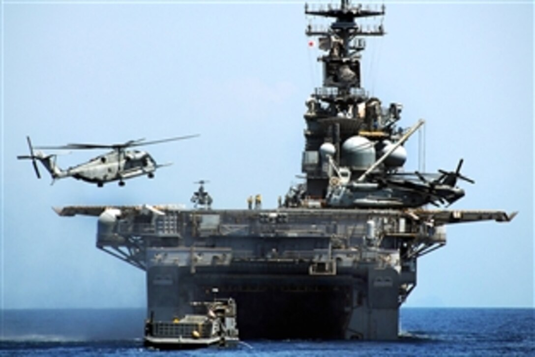 A CH-53E Sea Stallion helicopter lands aboard the amphibious assault ship USS Essex as a landing craft utility vehicle approaches to enter the well deck in the South China Sea, April 13, 2009. Essex is participating in Balikatan 2009, an annual bilateral exercise involving U.S. military and Armed Forces of the Philippines personnel.