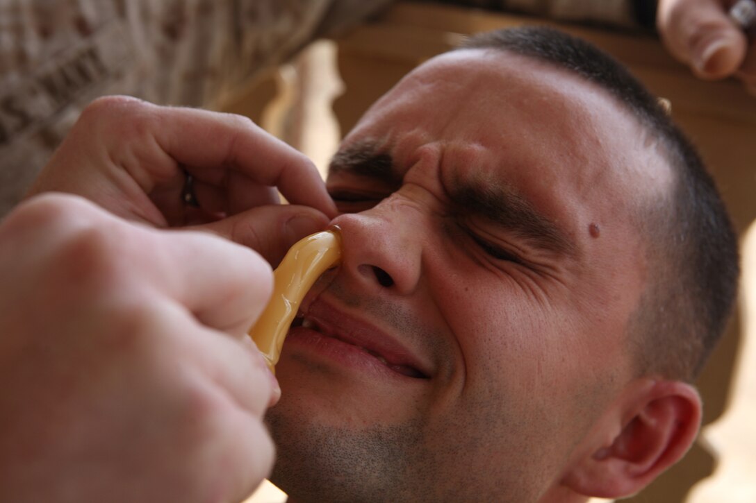 First Lieutenant Brendan Neagle, an assistant future operations officer with Headquarters Company, Regimental Combat Team 8, braces for the pain he is receiving from a rubber tube being shoved through his nasal cavity during the practical application phase of a combat lifesavers course held at the regimental aid station on April 16, 2009, at Camp Ripper, Iraq. The rubber tubing is used when a casualty cannot breathe from the mouth or because of blockage.