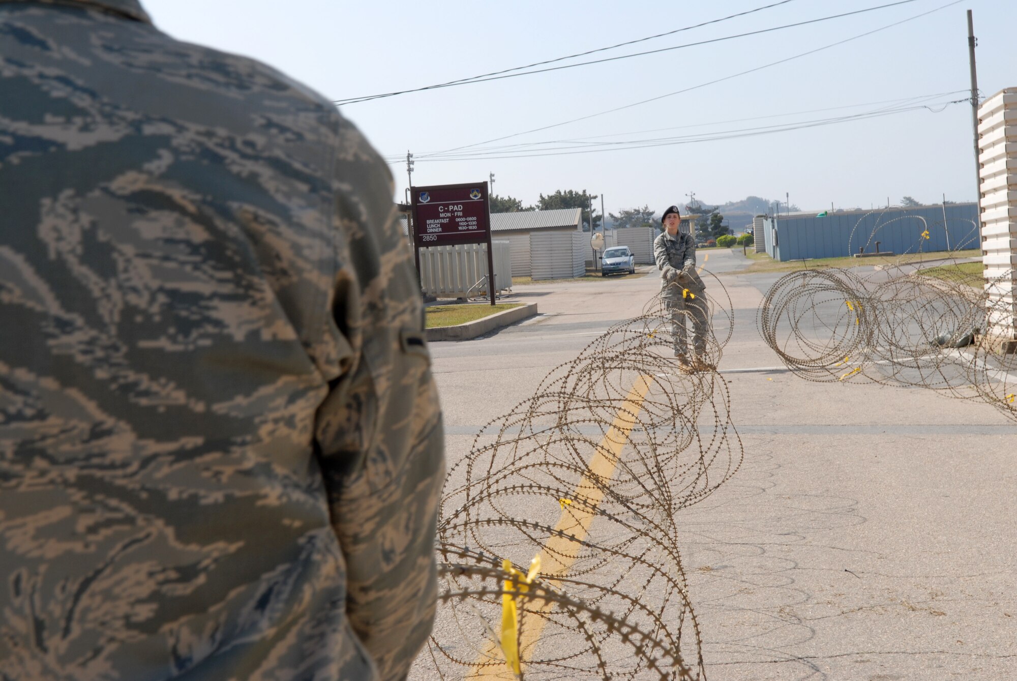 Airman Molly Bull and Airman 1st Class Molly Secotte, 8th Security Forces Squadron, unwind and place concertina-wire around  facilities on Kunsan Air Base, Republic of Korea, in preparation for the upcoming Operational Readiness Inspection April 17, 2009. Build up and hardening of facilities on base is a vital part of preparation for the upcoming ORI. (U.S. Air Force Photo by: Senior Airman Angela Ruiz)