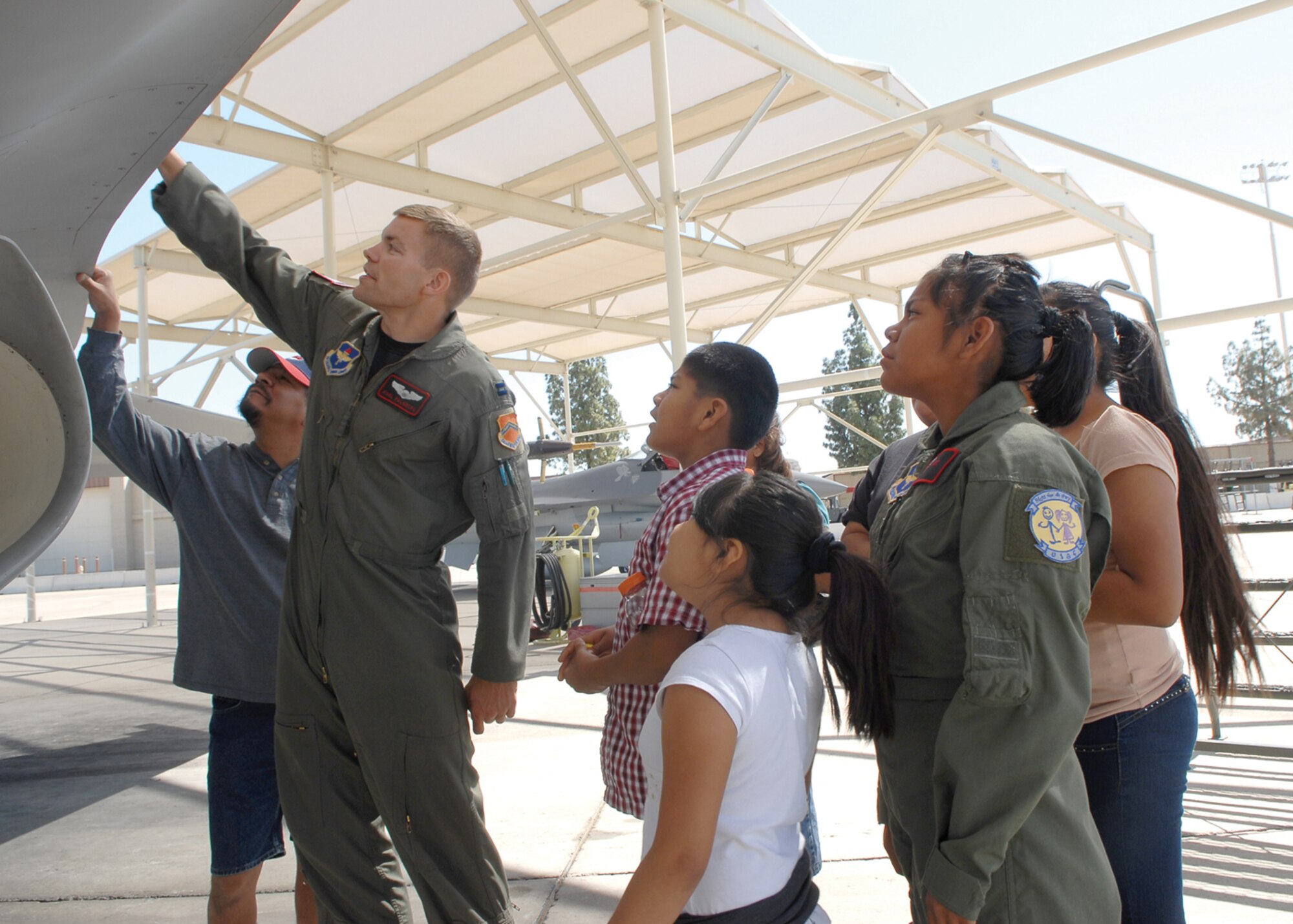 Capt. Karl Palmberg, 21st Fighter Squadron pilot, shows different parts on the F-16 Fighting Falcon to pilot-for-a-day Shawnee Lee and her family. (U.S. Air Force photo/ Airman 1st Class Ronifel Yasay.)