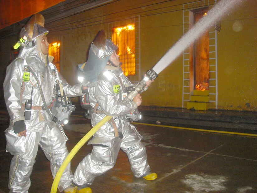 Joint Task Force-Bravo firefighters Staff Sgt. Peter Franko (left) and Senior Airman Daniel Meginness work to suppress a fire in Comayagua, Honduras, Wednesday evening.  Seven JTF-B firefighters responded to assist the Comayagua Fire Department with the blaze that erupted near the central plaza around 8 p.m.  (U.S. Air Force photo/Tech. Sgt. Rebecca Danét)