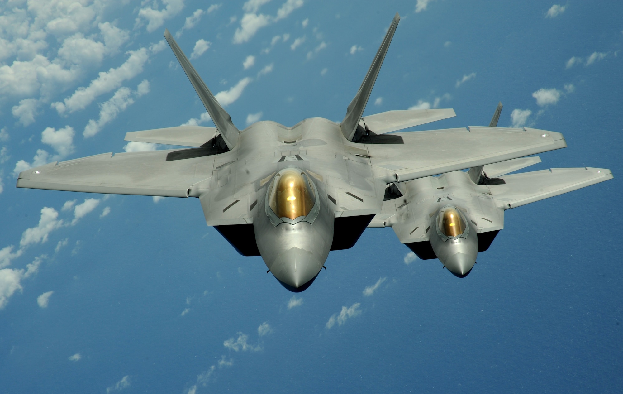 Two F-22 Raptors fly over the Pacific Ocean during a theater security mission. A Royal Australian Air Force pilot assigned to the 90th Expeditionary Fighter Squadron at Andersen Air Force Base, Guam, has had the opportunity to fly the F-22 Raptor as part of a pilot-exchange program. (U.S. Air Force photo/Master Sgt. Kevin J. Gruenwald)