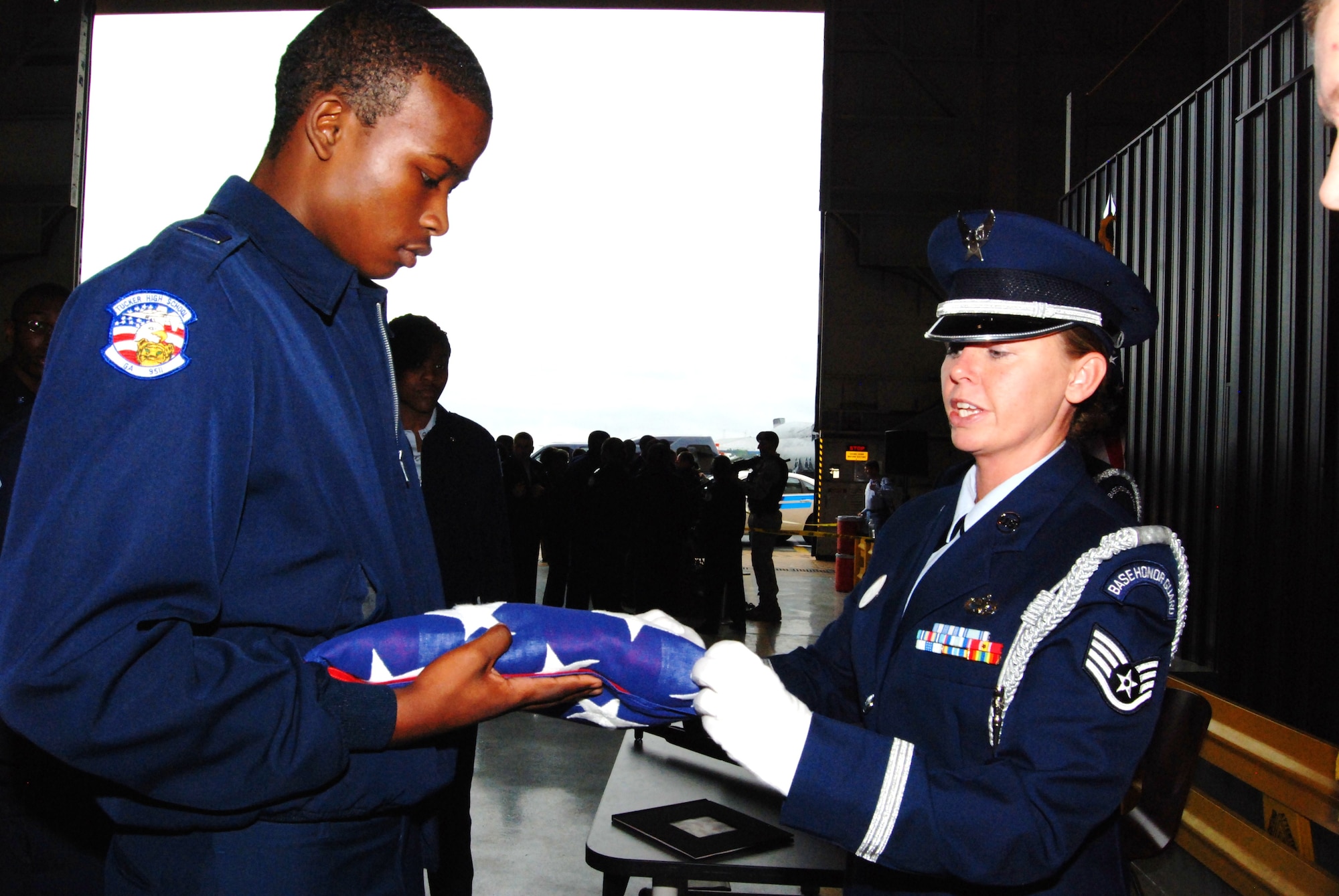Staff Sgt. Lisa Whitley, 94th Airlift Wing base honor guard, demonstrates the proper protocol for folding the flag April 15 for U.S. Air Force JROTC Cadet Capt. Dominic Plummer of Lovejoy High School, Atlanta, Ga. More than 1,000 cadets flew aboard a C-130 aircraft and toured static displays inside a hangar to learn more about U.S. Air Force careers.  (U.S. Air Force photo/Airman Chelsea Gitzen)
