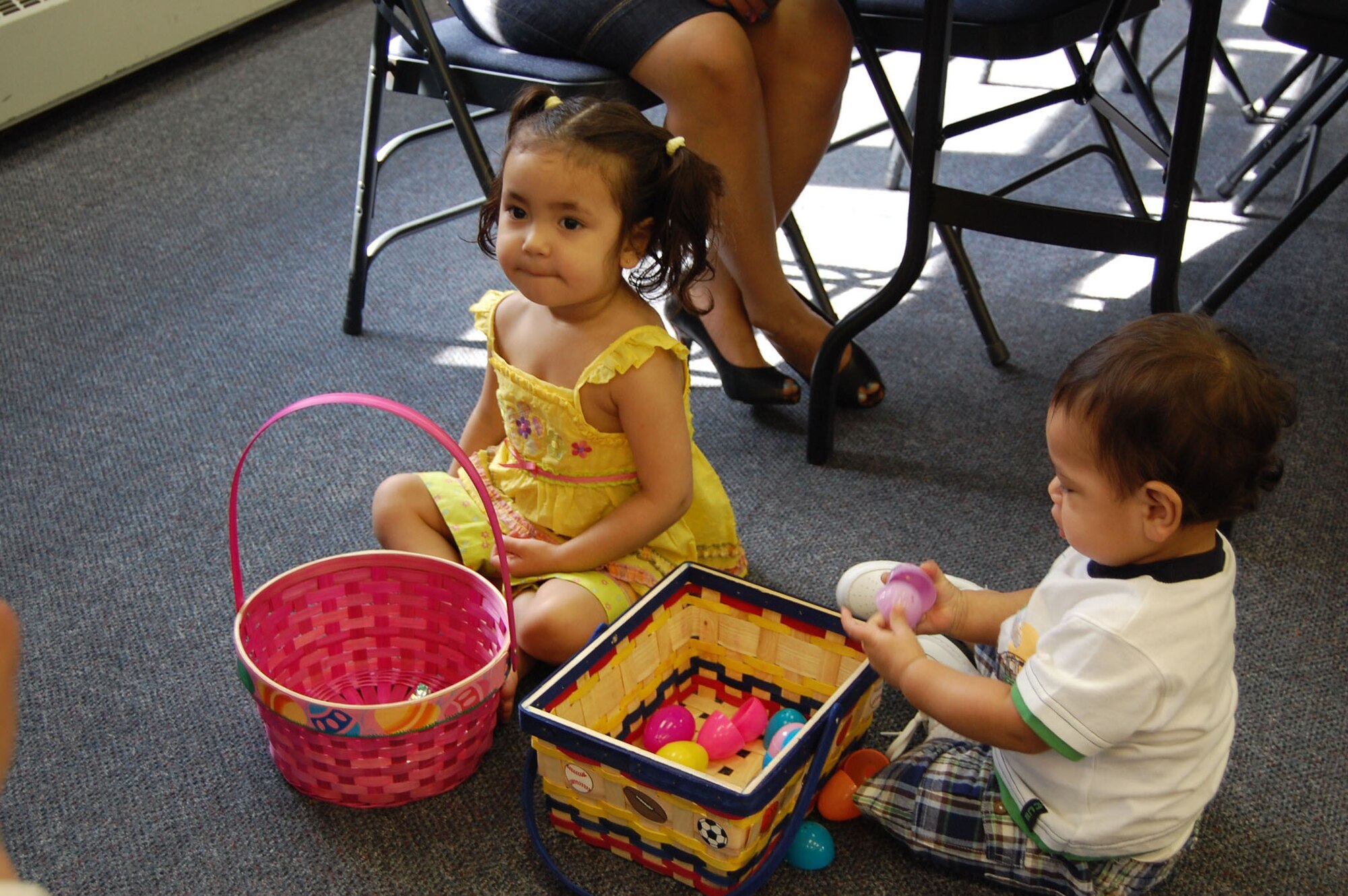 Ashley, 2, and her brother, Eli, 1, crack open their plastic eggs to find candy in them after searching for Easter eggs outside the base chapel April 11. (U.S. Air Force photo/Staff Sgt. Eydie Sakura)
