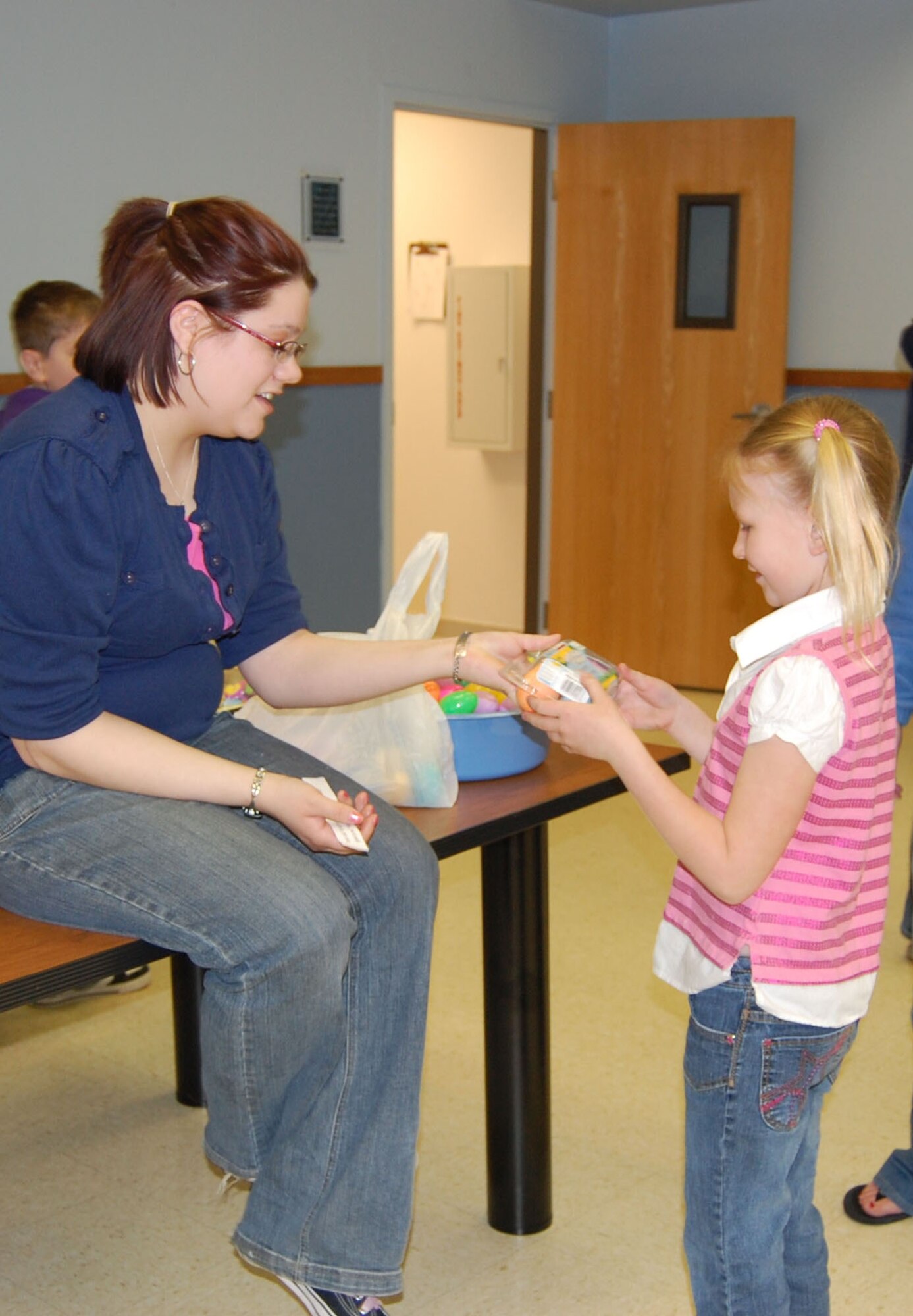 Senior Airman Katelyn Switzer, 341st Missile Wing chaplain assistant, gives a prize to Madison, 7, after she found one of the special eggs that contained a Bible verse at the base chapel’s annual Easter egg hunt April 11. (U.S. Air Force photo/Staff Sgt. Eydie Sakura)
