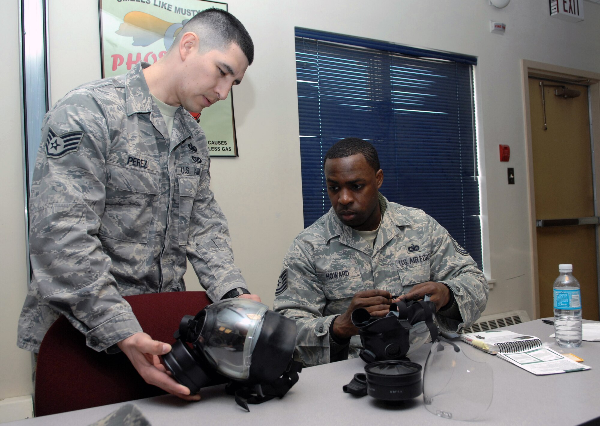 Staff Sgt. Oscar Perez (left) shows Tech Sgt. Chris Howard how to apply the second skin on a gas mask during a chemical warfare training class Apr. 7 at Eielson Air Force Base, Alaska. Chemical warfare training teaches Airmen how to survive and operate in hazardous environments whether deployed or at home station. (U.S. Air Force photo/Senior Airman Christopher Boitz)