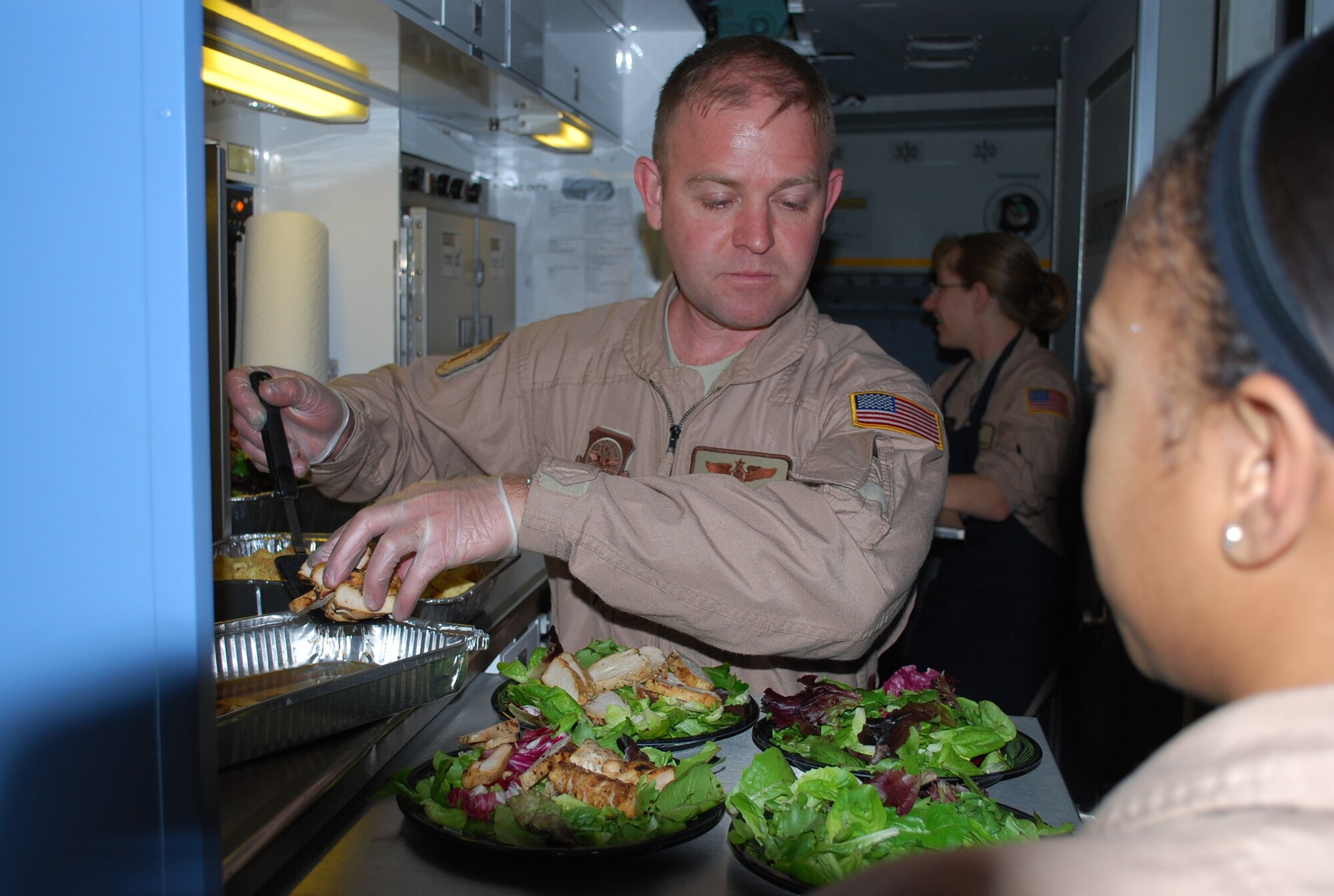 Tech. Sgt. Chris Wilson, 89th Airlift Wing, Operations Support Squadron, Andrews AFB, M.D., prepares salads for passengers during a NATO mission headed to Iraq. (Air Force photo/Major Bill Walsh)  