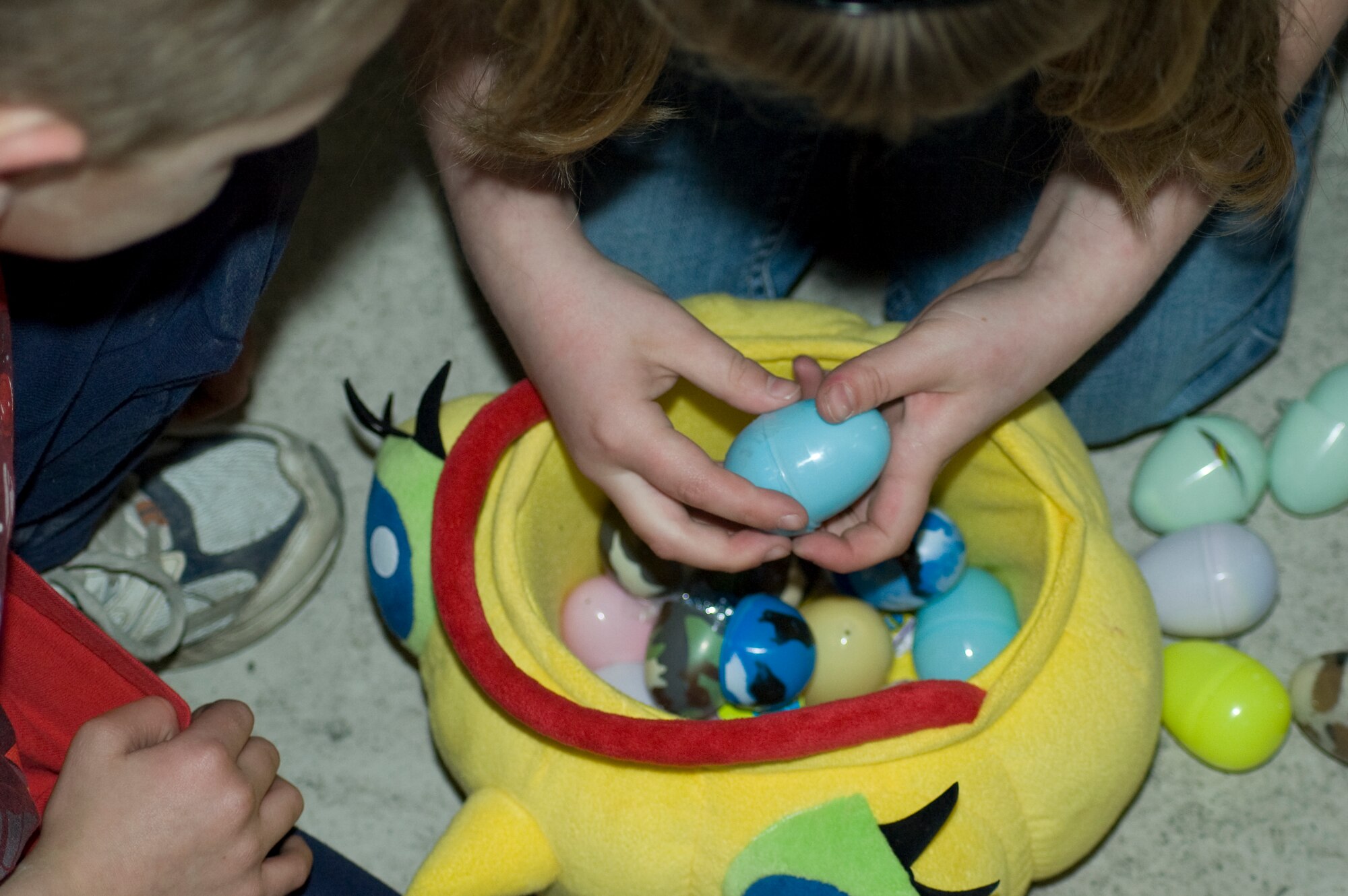 ELMENDORF AIR FORCE BASE, Alaska-- Children sit around their Easter basket opening their eggs one at a time to reveal the prize inside each one. This was after they just completed an Easter egg hunt which was put together by the 3rd Services Squadron at Hangar 5, here on April 11, 2009.