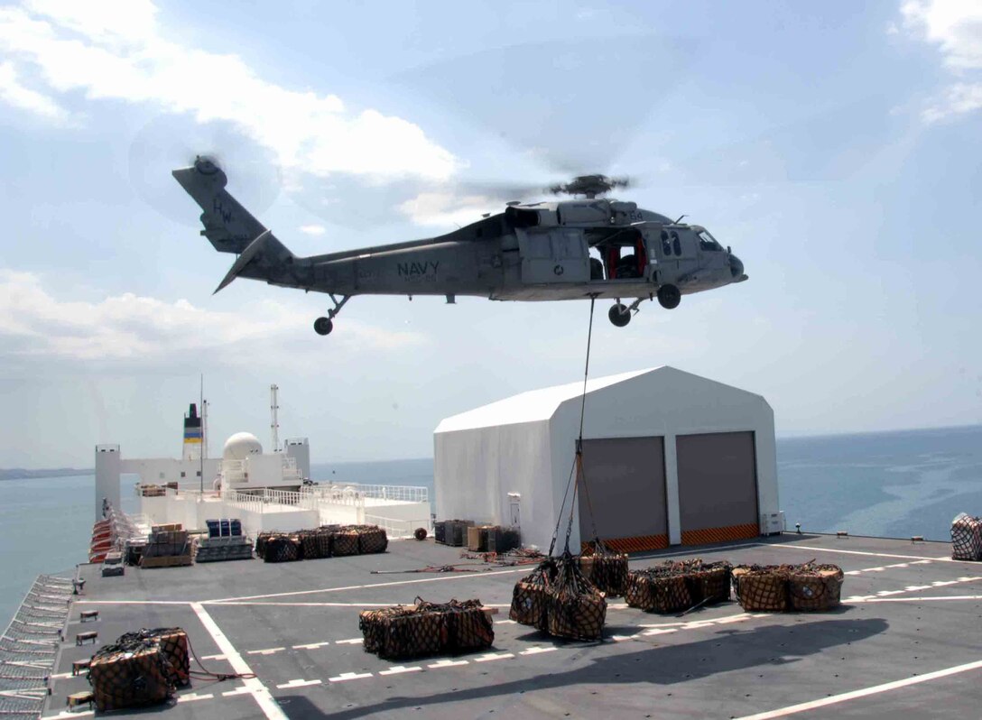 An U.S. Navy MH-60S helicopter carries one of the 333 loads of cargo off the hospital ship USNS Comfort, anchored off the shore of Port-Au-Prince, Haiti, April 14. The Comfort is on a four-month humanitarian and civic assistance mission to Latin America and the Caribbean as part of Continuing Promise 2009. The Comfort will visit seven countries including Antigua and Barbuda, Colombia, the Dominican Republic, El Salvador, Haiti, Nicaragua and Panama. (U.S. Army photo/Spc. Eric J. Cullen)