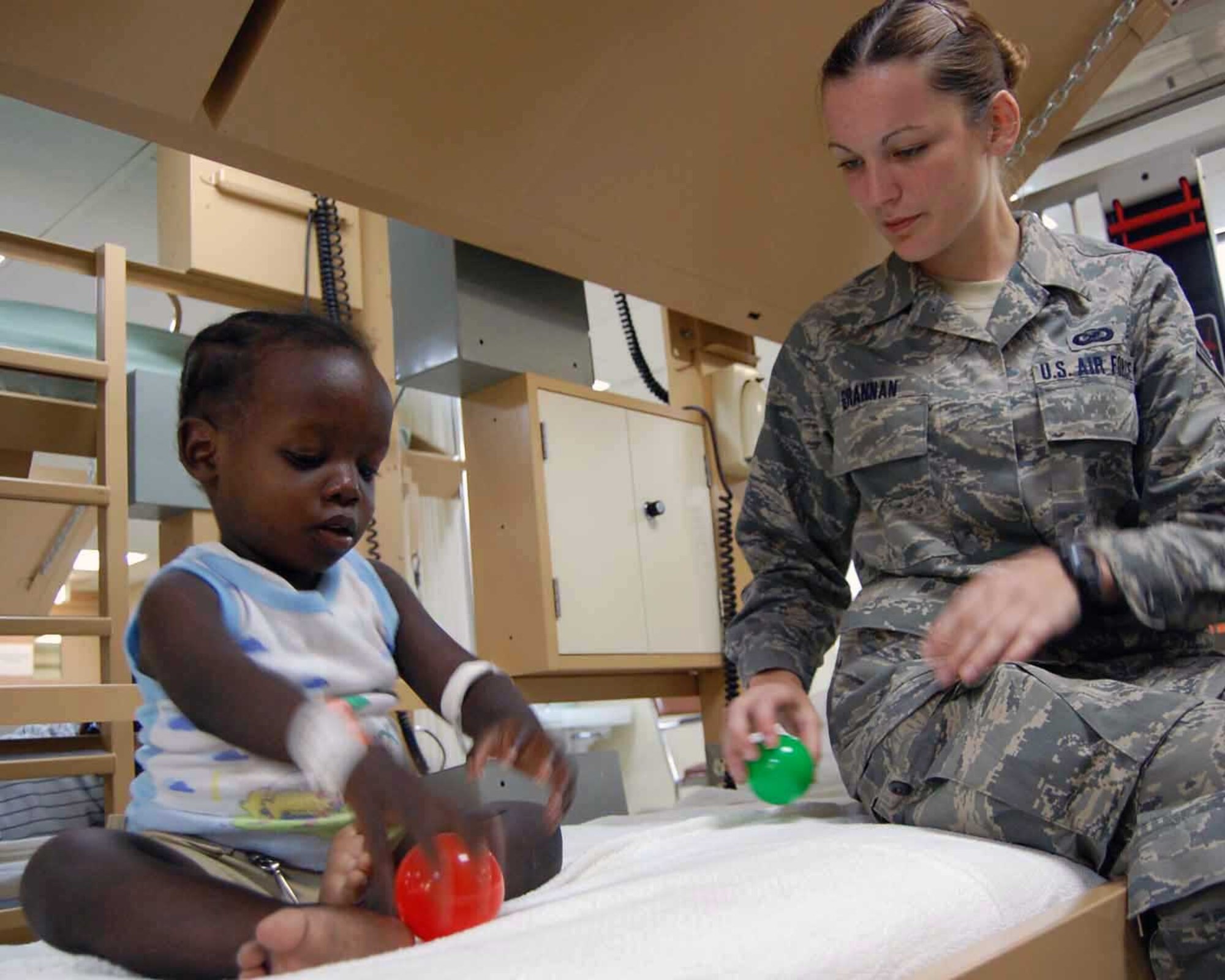 Airman 1st Class Danielle Grannin plays with Haitian child as he awaits surgery in the patient care ward April 12 aboard the hospital ship USNS Comfort. The Comfort, currently anchored off the shore of Port-Au-Prince, Haiti, is deployed on a four month humanitarian and civic assistance mission to Latin America and the Caribbean area.   (U.S. Air Force photo/Airman 1st Class Clara Karwacinski)