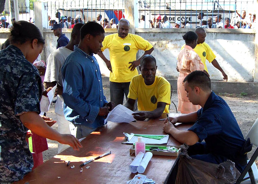 U.S. Navy Petty Officer 3rd Class Santana Wilks and Seaman Charles Carolus, a hospitalman apprentice, both assigned to the military hospital ship USNS Comfort, process patients in Port au Prince, Haiti, April 14, 2009.