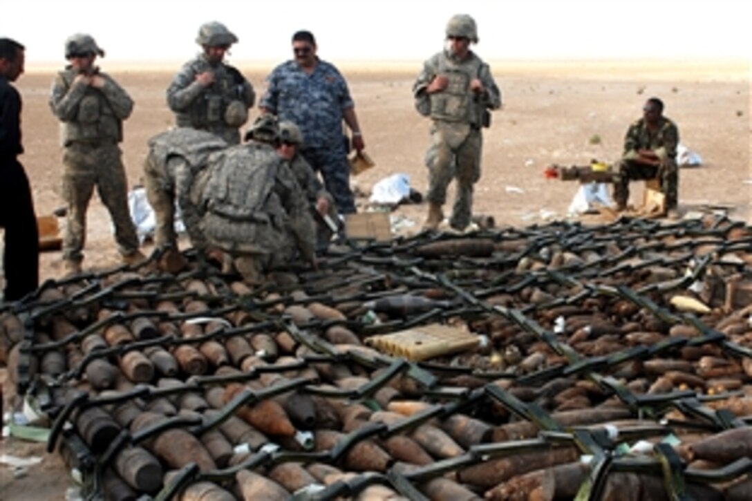 U.S. Army soldiers from the 760th Explosive Ordnance Disposal Company stand on nearly 8,000 pounds of inert and live munitions to inspect the work of Iraqi army and police in the desert near Karbala, Iraq, April 4, 2009.