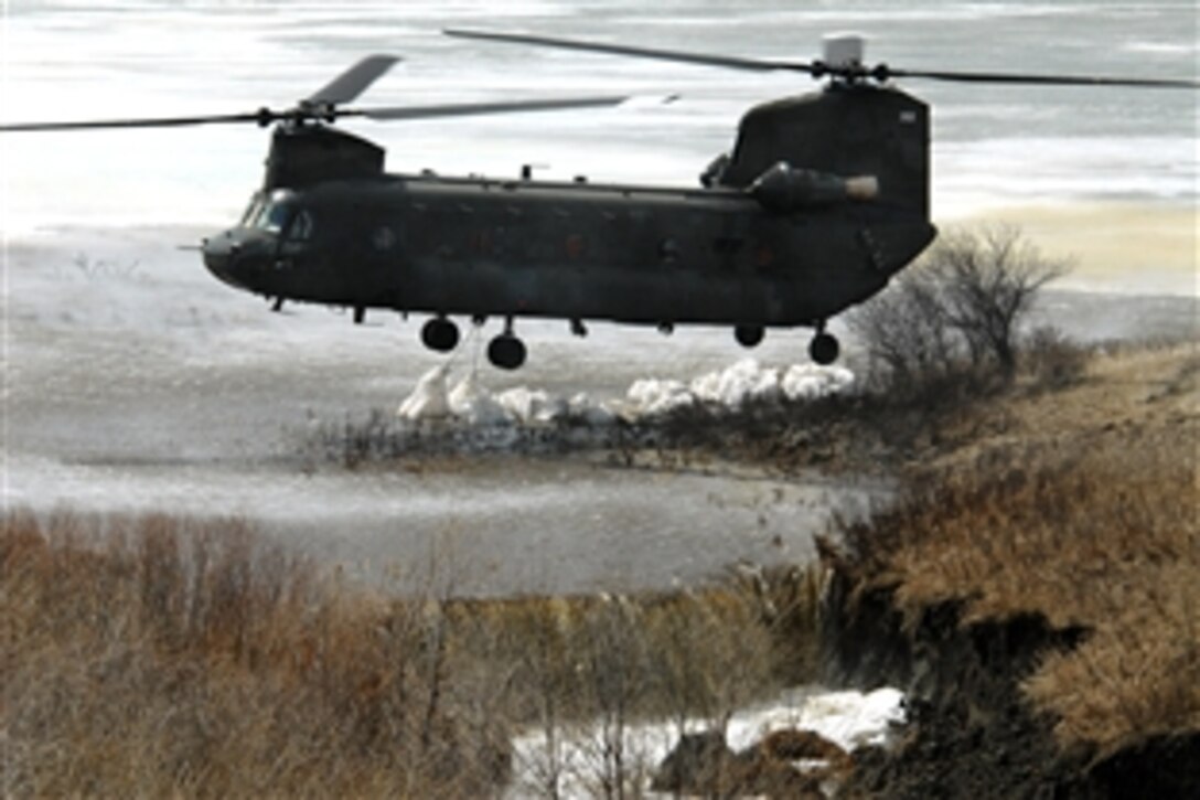 A North Dakota Air National Guard CH-47 Chinook helicopter drops several one-ton sandbags onto the spillway of the Clausen Springs Dam near Kathryn, N.D., April 15, 2009. The sandbags will help divert water away from an area of the dam being eroded by rising water, which also threatens to flood a local creek.