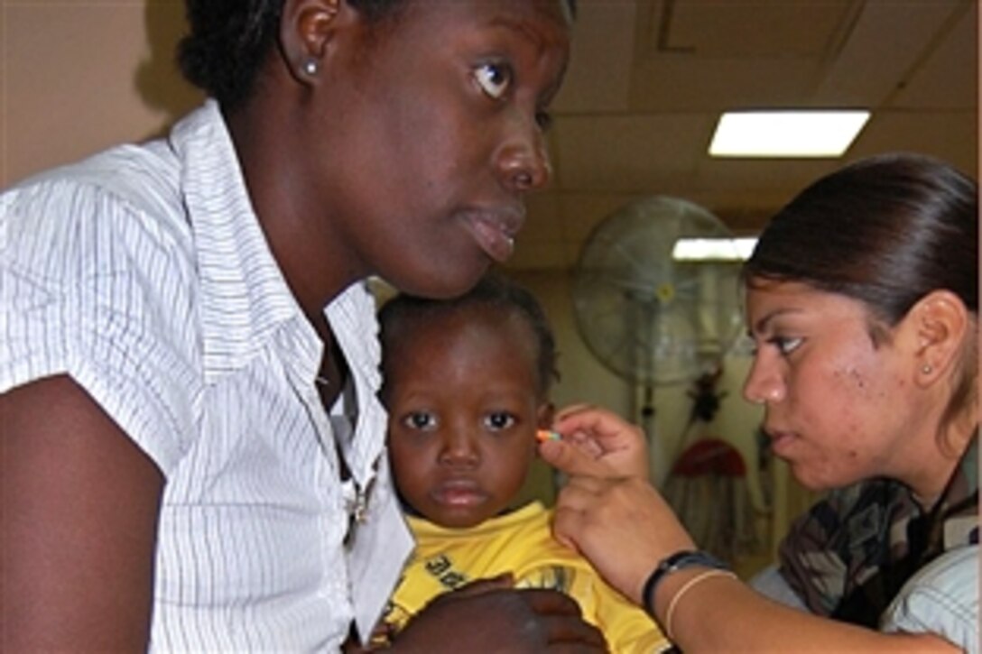 U.S. Navy Petty Officer 2nd Class Emily Garcia assists Kervins Guerrier and his mother Lonna Mercy with hearing protection for a helicopter ride back to Haiti from the military hospital ship USNS Comfort in Port au Prince, Haiti, April 15, 2009.