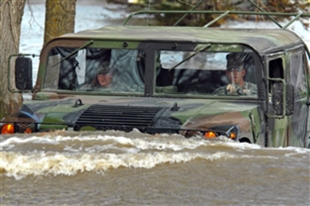 U.S. Army Staff Sgt. William Griffin, right, assigned to the 136th Combat Sustainment Support Battalion, drives a Humvee on a flooded road in Fort Ransom, N.D., April 15, 2009. Griffin and Spc. Jessica Sandberg, assigned to the 132nd Quartermaster Battalion, are making a welfare visit to a rural civilian whose home is surrounded by water.