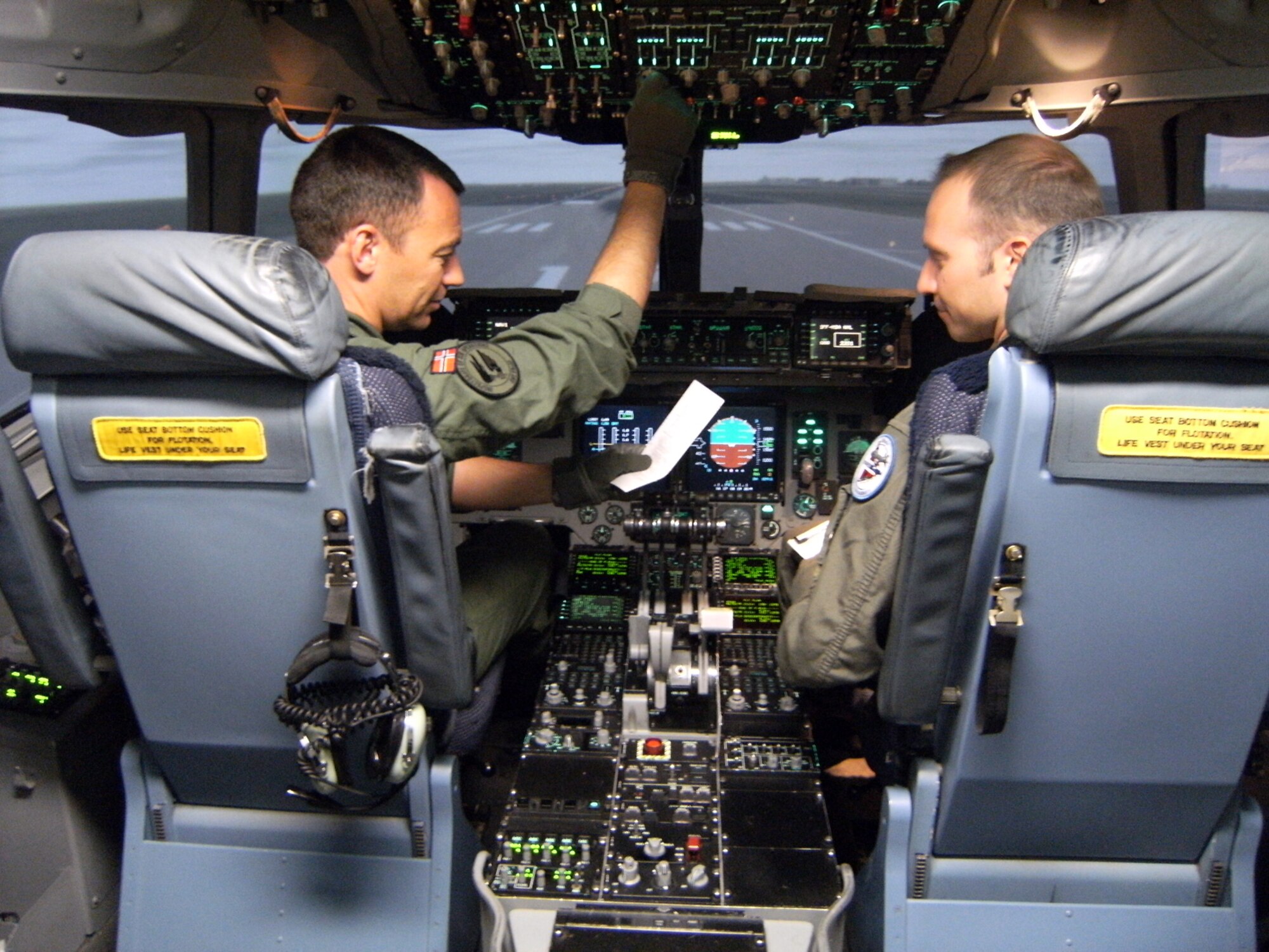 Maj. Christian Langfeldt (left) and Capt. Oeyvind Haaheim, Norwegian air force pilots training in a C-17 Globemaster III simulator, perform a pre-flight check April 16 before "takeoff."  They are enrolled in a C-17 pilot training course at the C-17 Aircrew Training Center at Altus Air Force Base, Okla. (U.S. Air Force photo/Senior Airman Clinton Atkins)