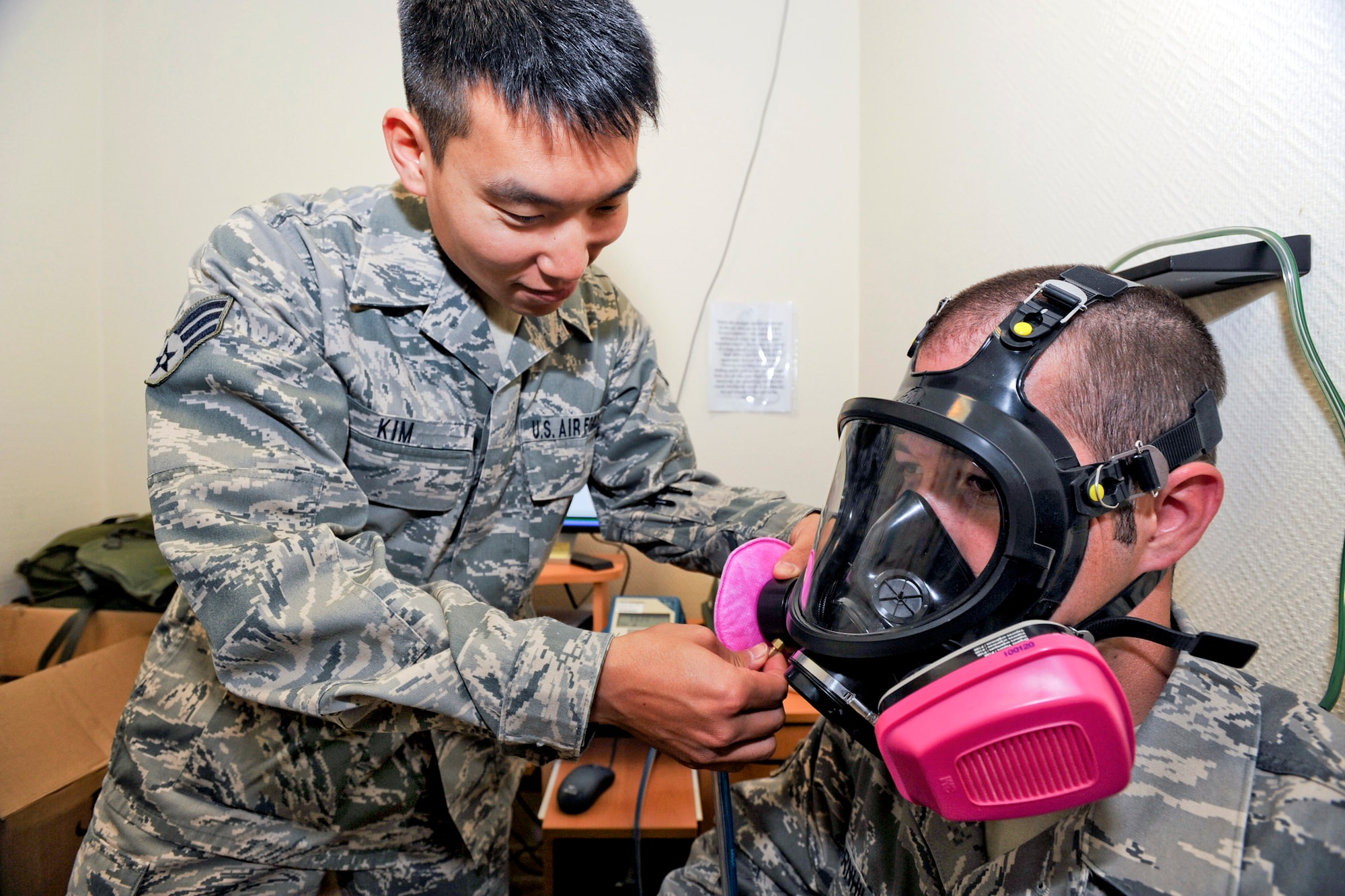Senior Airman Andrew Kim tightens Senior Airman Jonathan Barnhill's respirator mask before a fit test April 7 at an air base in Southwest Asia.  Respirators must be periodically tested to ensure they provide adequate protection. Airman Kim is  a bioenvironmental engineering technician with the 379th Medical Group and Airman Barnhill is assigned to the 379th Expeditionary Maintenance Squadron. (U.S. Air Force photo/Staff Sgt. Joshua Garcia)