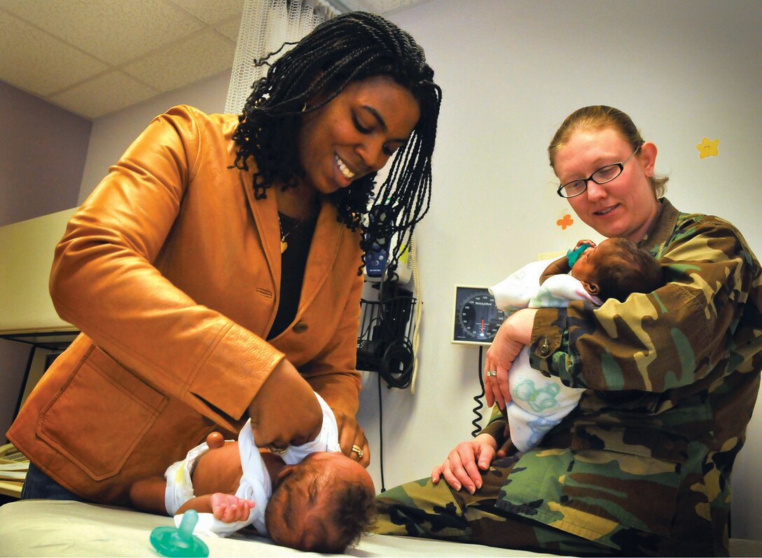 Capt. Melinda B. Batman, 779th Medical Group pediatrician, exams one of two 4-month-old twins, Nicole and Victoria Hopkins, as mother, Briona Hopkins, changes her other daughters clothes during a routine well baby appointment recently. (U.S. Air Force photo/ Tech. Sgt. Suzanne M. Day)