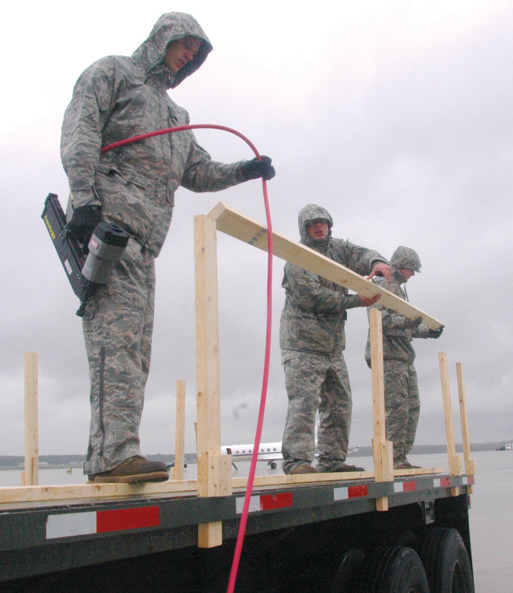 Senior Airman Zachary Mummert, left, 316th Civil Engineer Squadron structual journeyman prepares to secure a railing atop a flatbed platform while other members steady the frame Wednesday prior to the arrival of the media covering the return of crewmembers from the American ship Maersk Alabama. (U.S. Air Force photo/ Bobby Jones)
