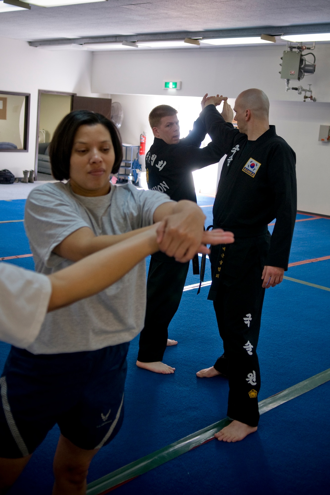MISAWA AIR BASE, Japan -- Capt. Angela Batts, sexual assault response coordinator, practices an escape technique as instructors 1st Lt. Brian Myers and Master Sgt. Jeremy Fuegi demonstrate in the background during a women's self-defense class April 16, 2009. Four classes are being held throughout April in support of Sexual Assault Awareness Month. (U.S. Air Force photo by Senior Airman Jamal D. Sutter)