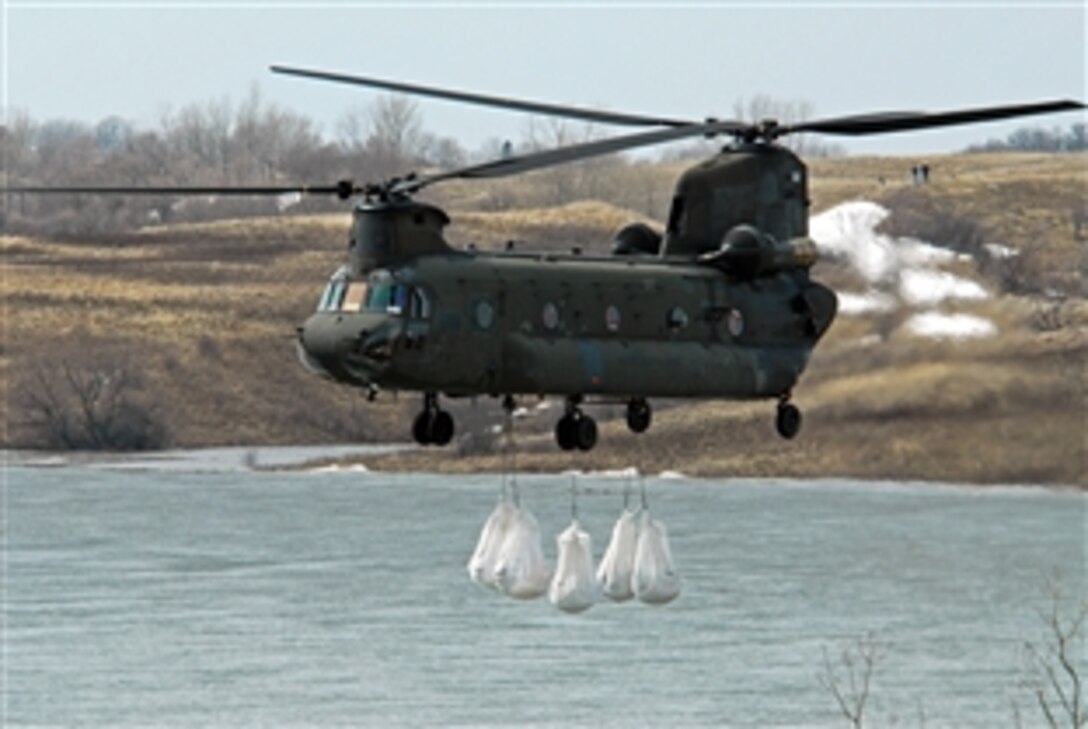 A North Dakota Air National Guard CH-47 Chinook helicopter drops several one-ton sandbags onto the spillway of the Clausen Springs Dam near Kathryn, N.D., April 15, 2009. The sandbags will help divert water away from an area of the dam being eroded by rising water, which also threatens to flood a local creek.