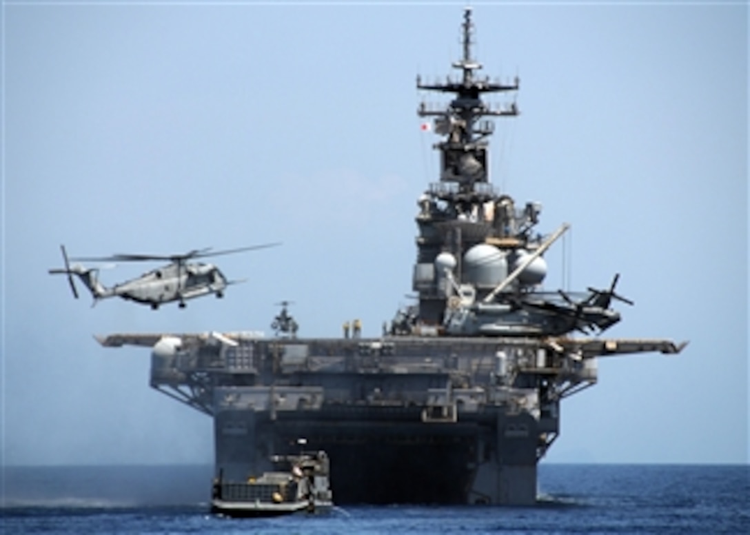 A U.S. Navy CH-53E Sea Stallion helicopter, assigned to the Air Combat Element of the U.S. Marine Corps 31st Marine Expeditionary Unit, lands on the flight deck of the forward deployed amphibious assault ship USS Essex (LHD 2) in the South China Sea on April 13, 2009.  Also a landing craft utility vehicle approaches the Essexís well deck.  The Essex has been invited by the Republic of the Philippines to participate in Balikatan 2009, which is an annual combined, joint-bilateral exercise involving U.S. military and Armed Forces of the Philippines personnel as well as subject matter experts from Philippine civil defense agencies.  