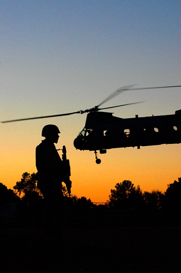 While a CH-46 Sea Knight lifts off behind him, Lance Cpl. Charles E. Weber, a radio operator with the 3rd Low Altitude Air Defense Battalion, guards the perimeter a makeshift landing zone at Centennial Middle School in Yuma, Ariz., during an exercise simulating the evacuation of U.S. citizens from a foreign nation in crisis April 17, 2009. For special exercises throughout the year, the city of Yuma allows the Marine Corps to use local parks and school sports fields as training areas, which provide real urban locales that couldn't easily be simulated. During the exercise, numerous CH-46s and CH-53 Sea Stallion helicopters quickly landed and launched again, dropping off Marines and rescuing role players. The exercise was part of the latest Weapons and Tactics Instructors course taught by the Marine Aviation Weapons and Tactics Squadron 1, based at the Marine Corps Air Station in Yuma. The course teaches Marine aviators and other support personnel from across the Corps the latest in air tactics so students can graduate as instructors who develop future training for their units. Weber is a 20-year-old native of Schwenksville, Pa.