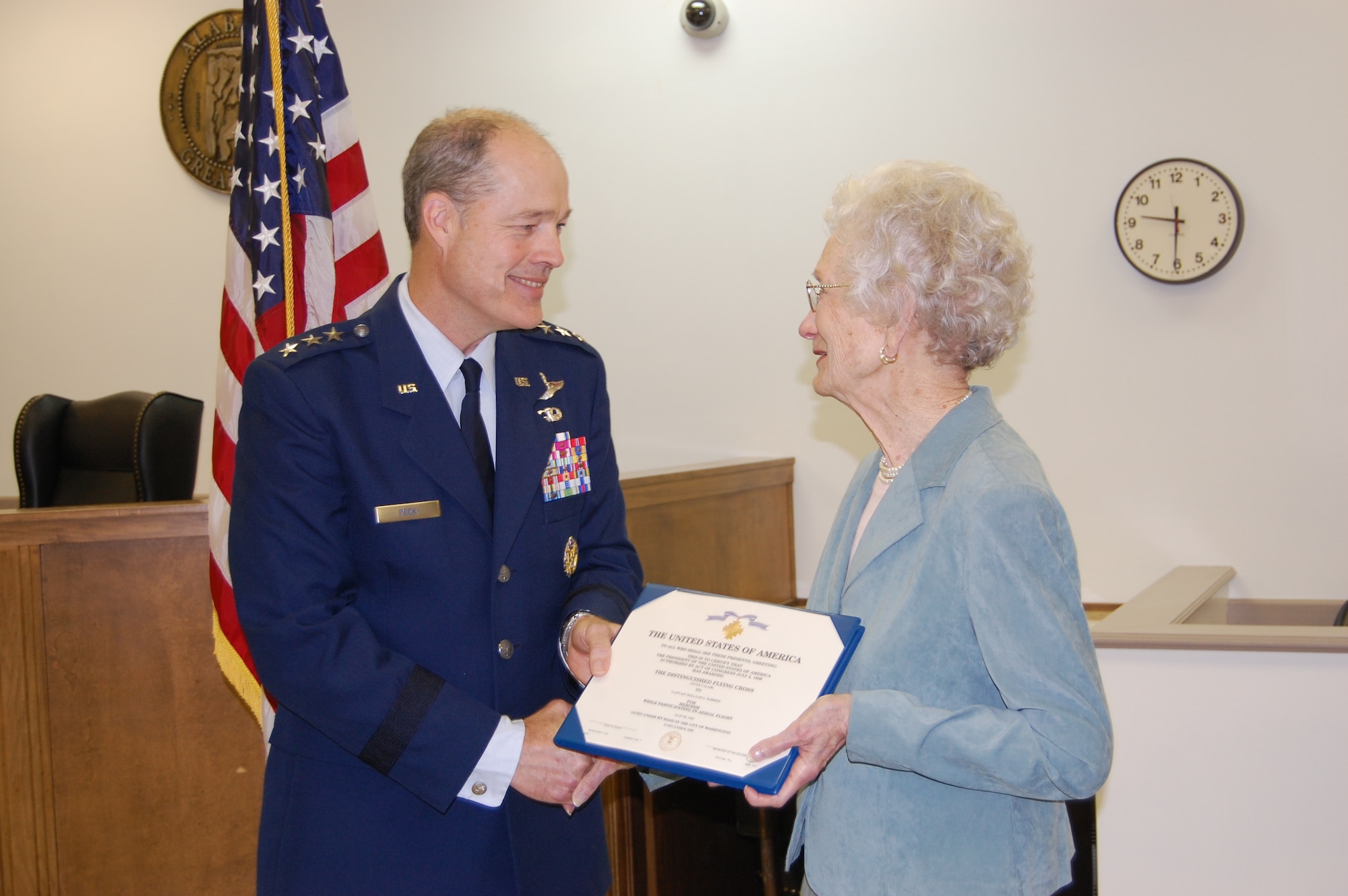 Lt. Gen. Allen Peck, Air University commander, presents Mrs. William (Doris) Norred with her late-husband's Distinguished Flying Cross with Valor on Monday. Capt. William Norred's military records were reviewed, and it was determined he earned the DFC on a combat mission during World War II. (Air Force photo by Carl Bergquist)