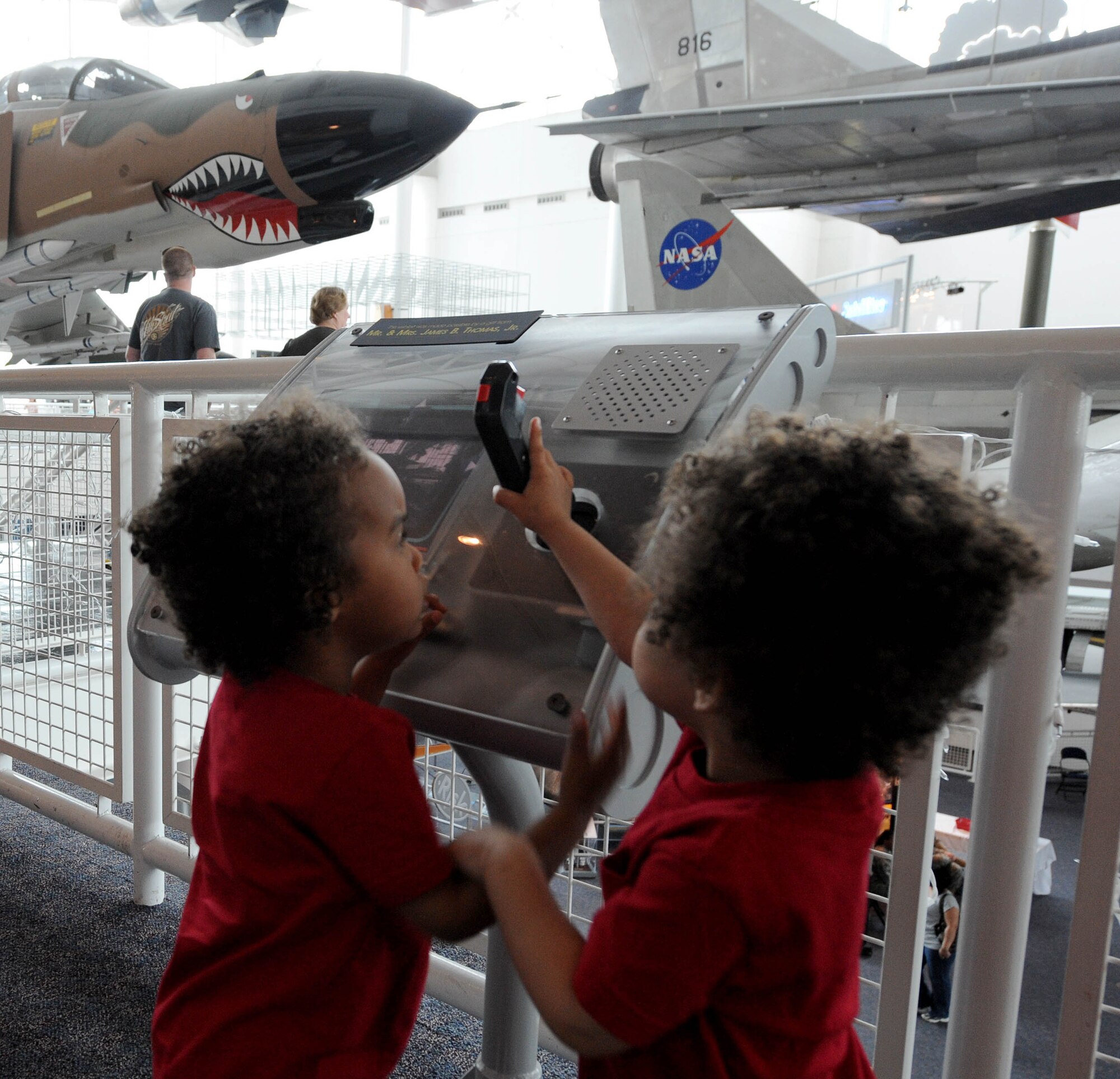 LANGLEY AIR FORCE BASE, Va. -- Two-year-old twins play with a joystick at the Virginia Air & Space Center April 19. Hampton Roads Air Force Week offers free admission to the center and IMAX movie “Fighter Pilot: Operation Red Flag” through April 23 for the public.This event offered Air Force Recruiting Service “Inspire Tour” Displays and Langley AFB unit displays. (U.S. Air Force photo/Airman Rebecca Montez)