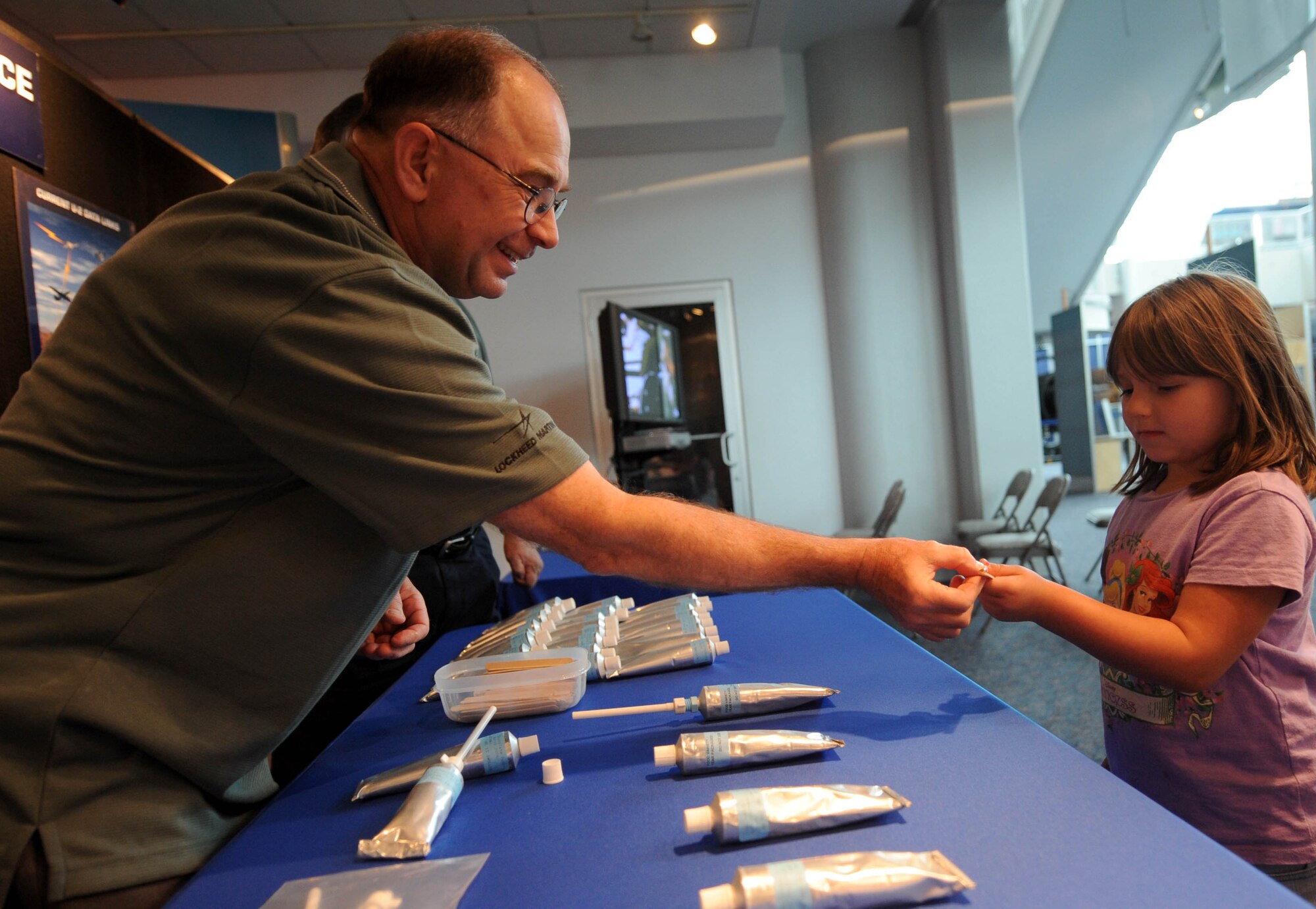 LANGLEY AIR FORCE BASE, Va. -- James Bullard, a logistic integration support engineer for the U-2 Spy Plane "Dragon Lady" offers a sample of pilot "food in a tube" to Brittany, age 9, at the Virginia Air & Space Center during Hampton Roads Air Force Week April 19.  This event offered free admission to the center, free IMAX movie “Fighter Pilot: Operation Red Flag,” Air Force Recruiting Service “Inspire Tour” Displays, and Langley AFB unit displays (U.S. Air Force photo/Airman Rebecca Montez)