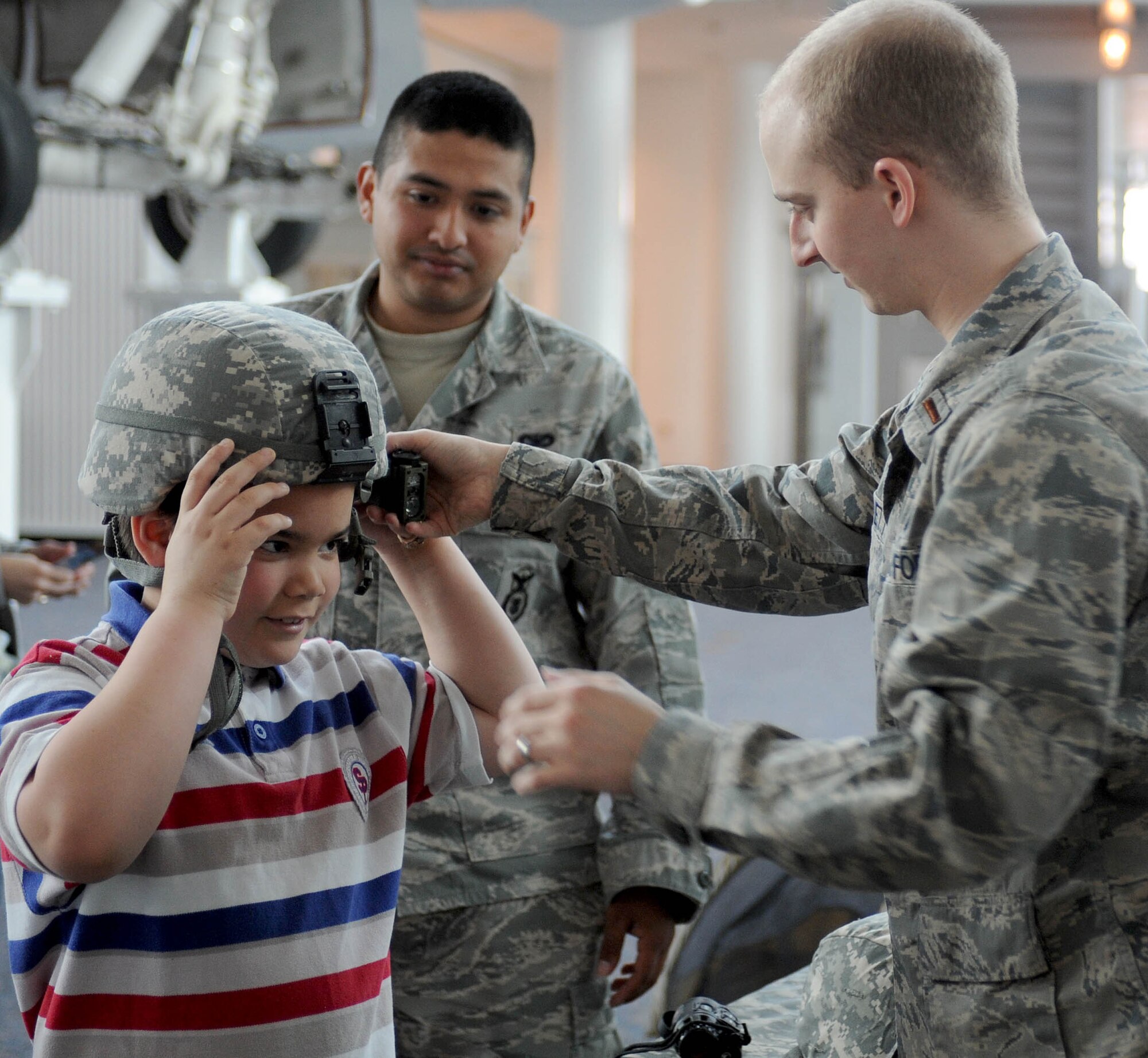 LANGLEY AIR FORCE BASE, Va. -- Richard Griswald, age 7, tries on a helmet with the help of 2nd Lt. Joseph Eanett, 1st Security Forces Squadron, at the Virginia Air & Space Center exhibits during Hampton Roads Air Force Week  April 19.  This event offered free admission to center, free IMAX movie “Fighter Pilot: Operation Red Flag,” Air Force Recruiting Service “Inspire Tour” Displays, and Langley AFB unit displays. (U.S. Air Force photo/Airman Rebecca Montez) 