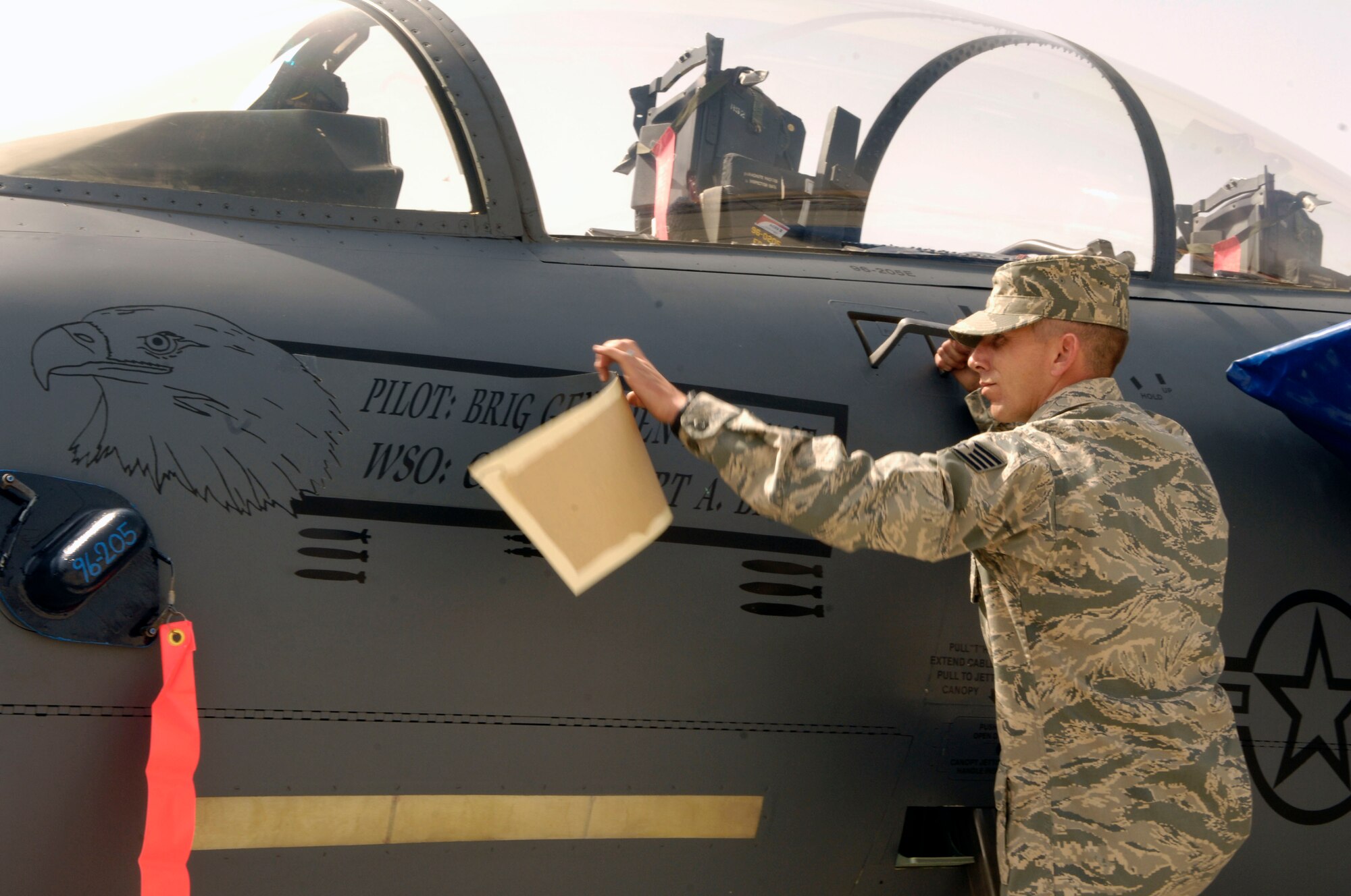 Staff Sgt. Robert Burns, 455th Expeditionary Maintenance Group, removes a sticker off of the 455th Air Expeditionary Wing flagship aircraft to expose Col. Steven Kwast?s name dedicating it to him while under his command for the next year. Colonel Kwast took command of the 455th AEW during a ceremony at Bagram Air Field, Afghanistan, April 18. (U.S. Air Force photo/Senior Airman Steven Doty)(Released)
