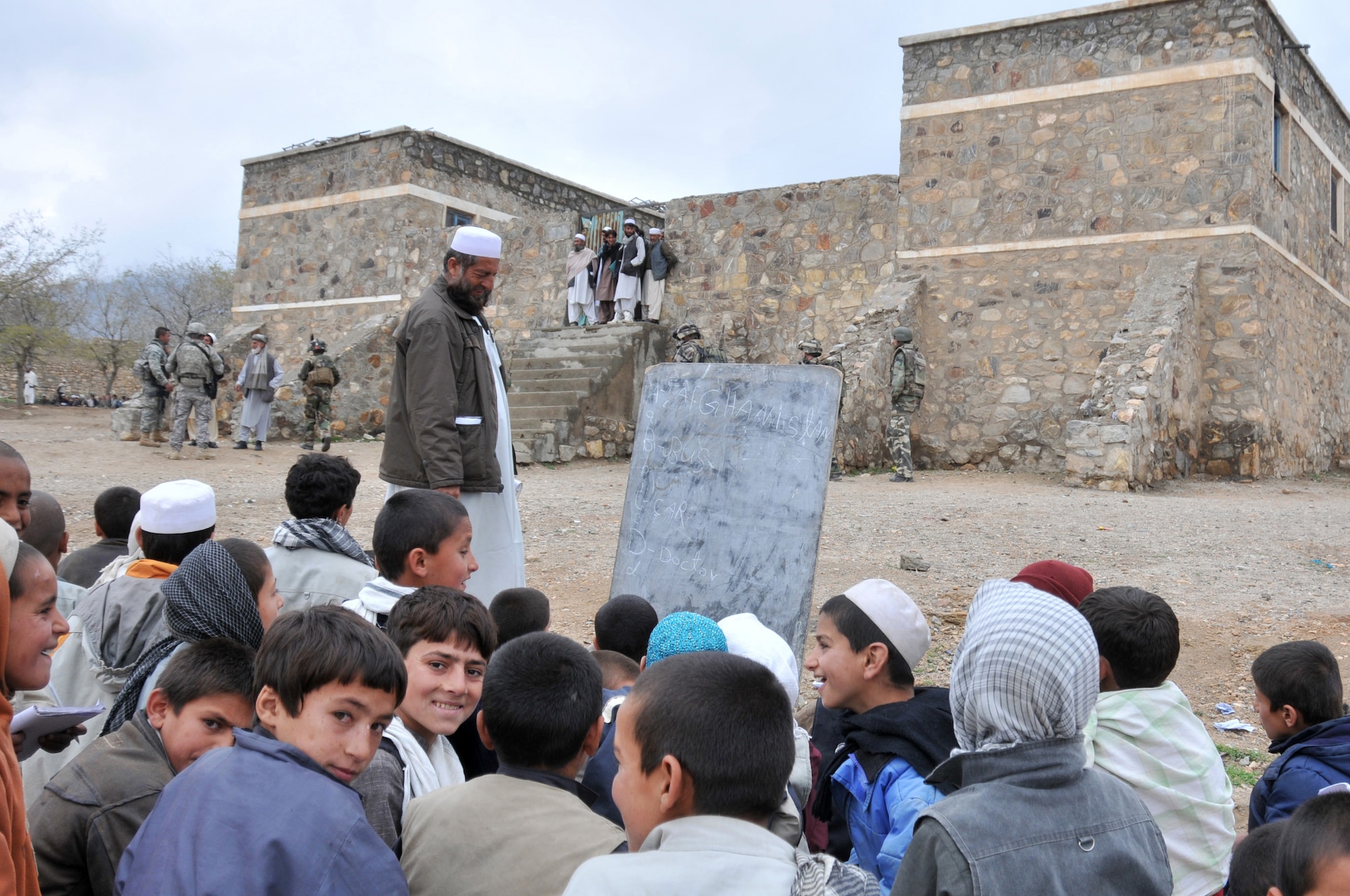 Afghan school children learn English while engineers from the Kapisa and Parwan Provincial Reconstruction Team inspect the school building near the Alasay District Center on April 6. The local government prioritized this school as a development project for the PRT to work on in Alasay District, Kapisa province.  (U.S. Air Force photo by Chief Master Sgt. John Zincone)