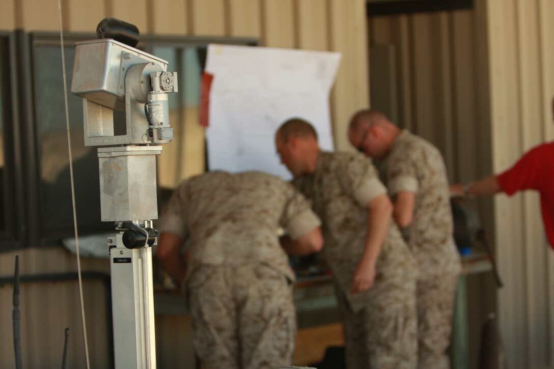 The camera on the Remote Ordinance Neutralization System robot made by Remotec stands as Explosive Ordinance Disposal technicians with Marine Wing Support Squadron 374 perform maintenance on parts of its chassis.