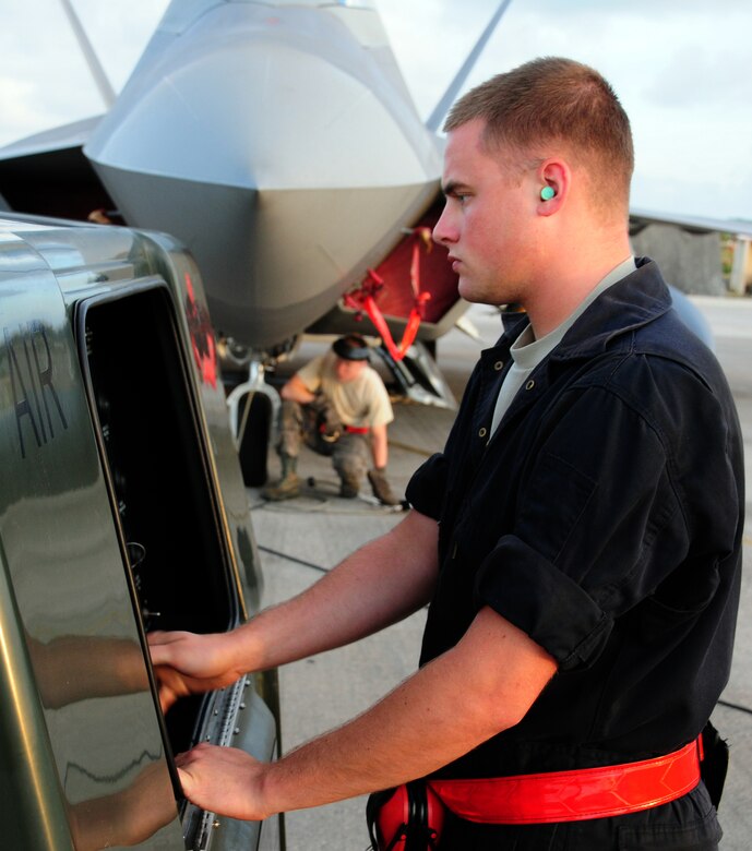 Airman 1st Class's Matt Porter(foreground) and Joe Weinert, crew chiefs with the 36th Expeditionary Aircraft Maintenance Squadron, adjust the tire pressure of an F-22 Raptor the night before its departure form Andersen Air Force Base, Guam, April 15. The 90th Expeditionary Fighter Squadrons  90-day deployment to Andersen Air Force Base, Guam, consisiting of more than 250 Airmen and 14 aircraft, came to a close April 16.  the 90th EFS was deployed here via a regularly scheduled Air Expeditionary Force rotation, demonstrating U.S. commitment to peace and stability throughout the Pacific region.(U.S. Air Force photo/Senior Airman Ryan Whitney)